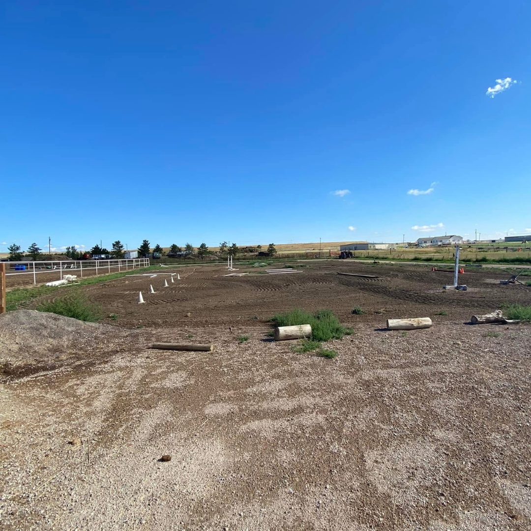 Construction site with cleared dirt, construction cones, and equipment under a clear blue sky.