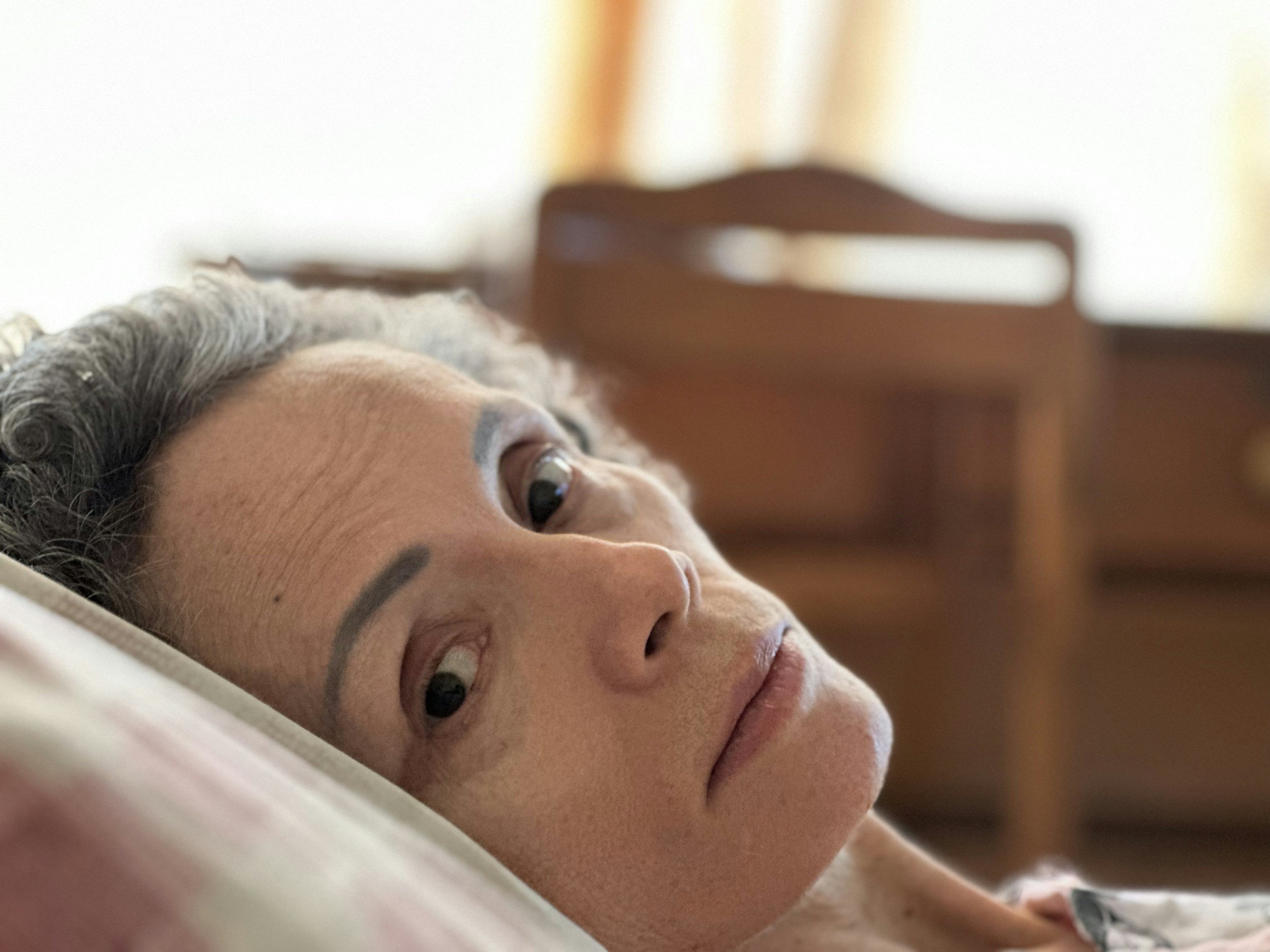 Older woman lying in bed looking worried