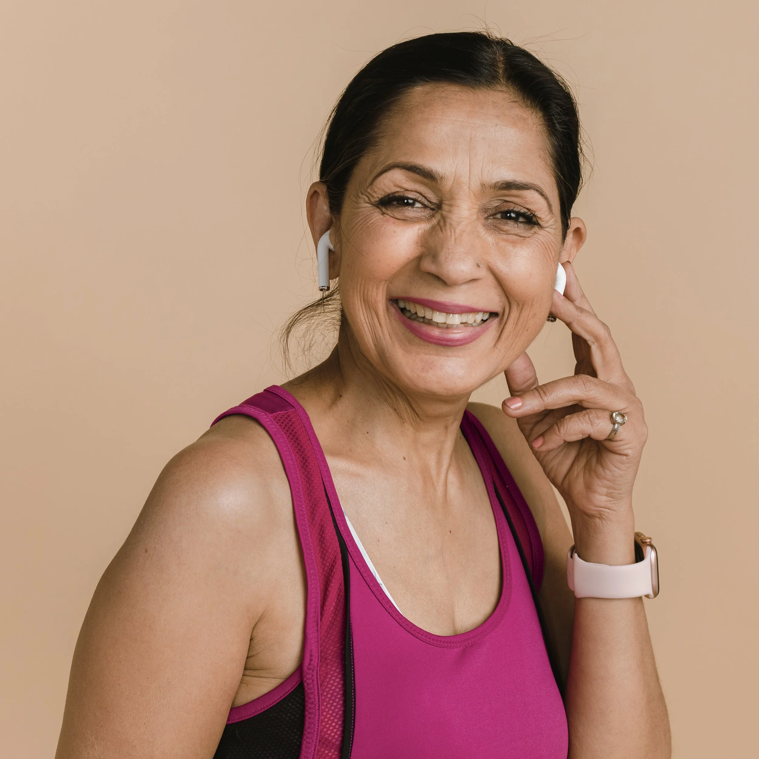 Smiling woman in a red tank top listens to music indoors