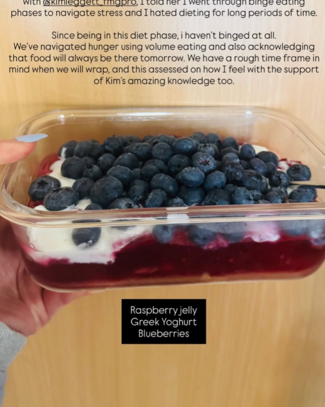 Container of layered dessert with blueberries on top, labeled as raspberry jelly, Greek yogurt, and blueberries.