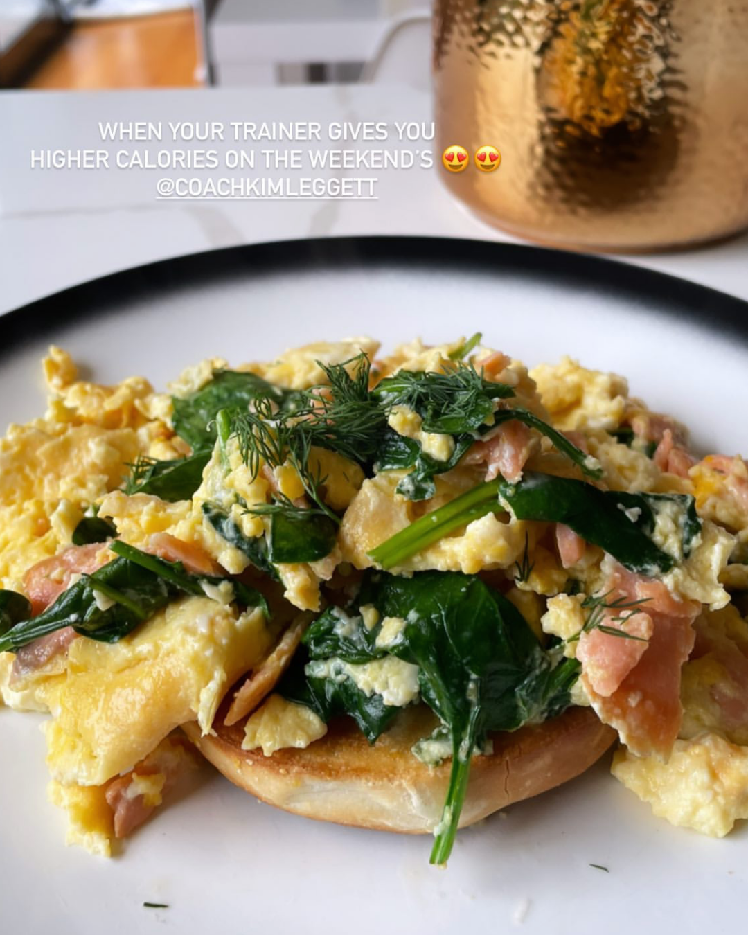 Close-up of scrambled eggs with spinach, herbs, and smoked salmon on a plate.