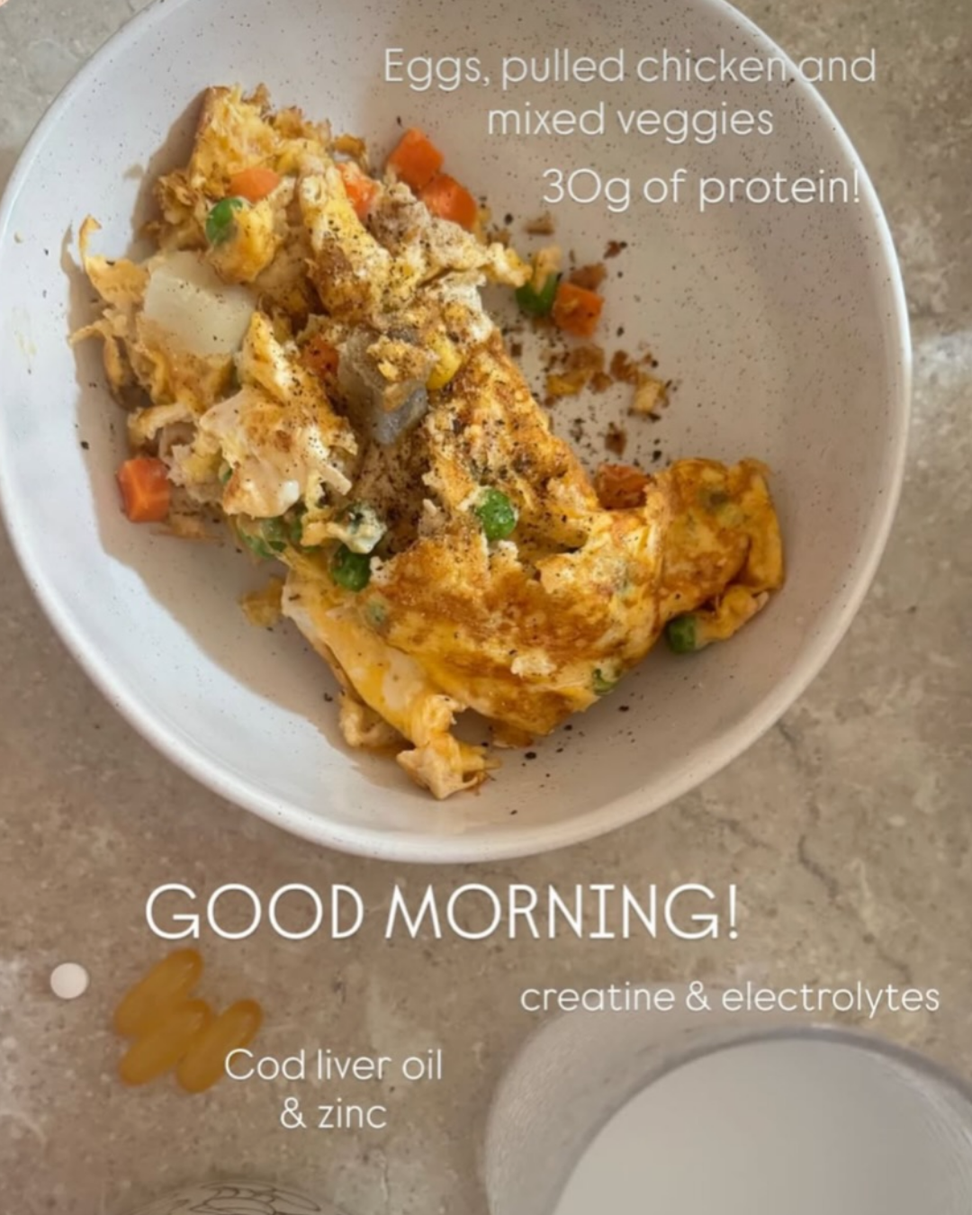 A bowl of scrambled eggs with pulled chicken and mixed vegetables, garnished with black pepper. Text overlay describes the dish's protein content and ingredients, including cod liver oil and zinc.