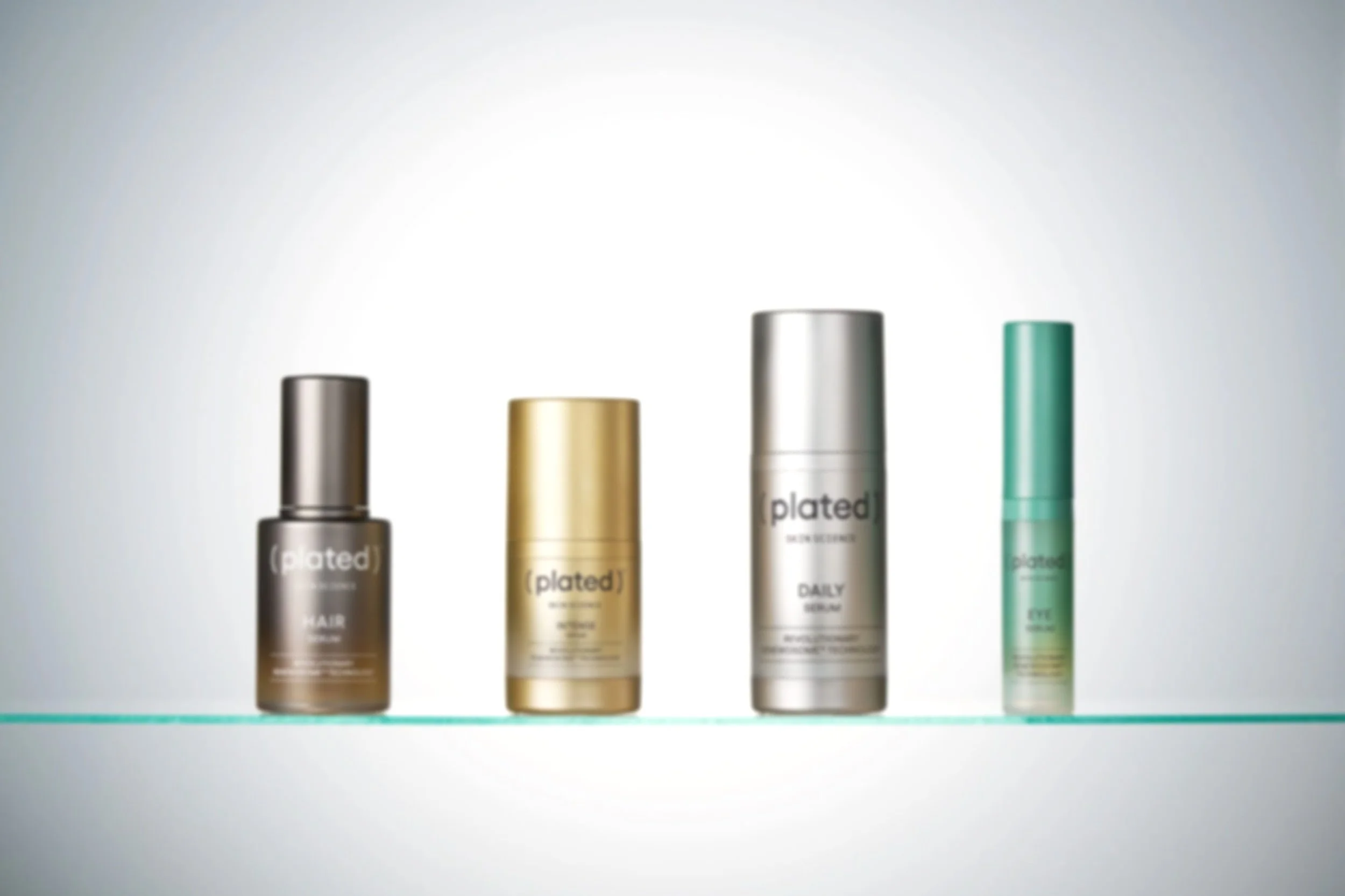 Four skincare or cosmetic bottles on a glass shelf, each with different colored caps and labels, against a white background.