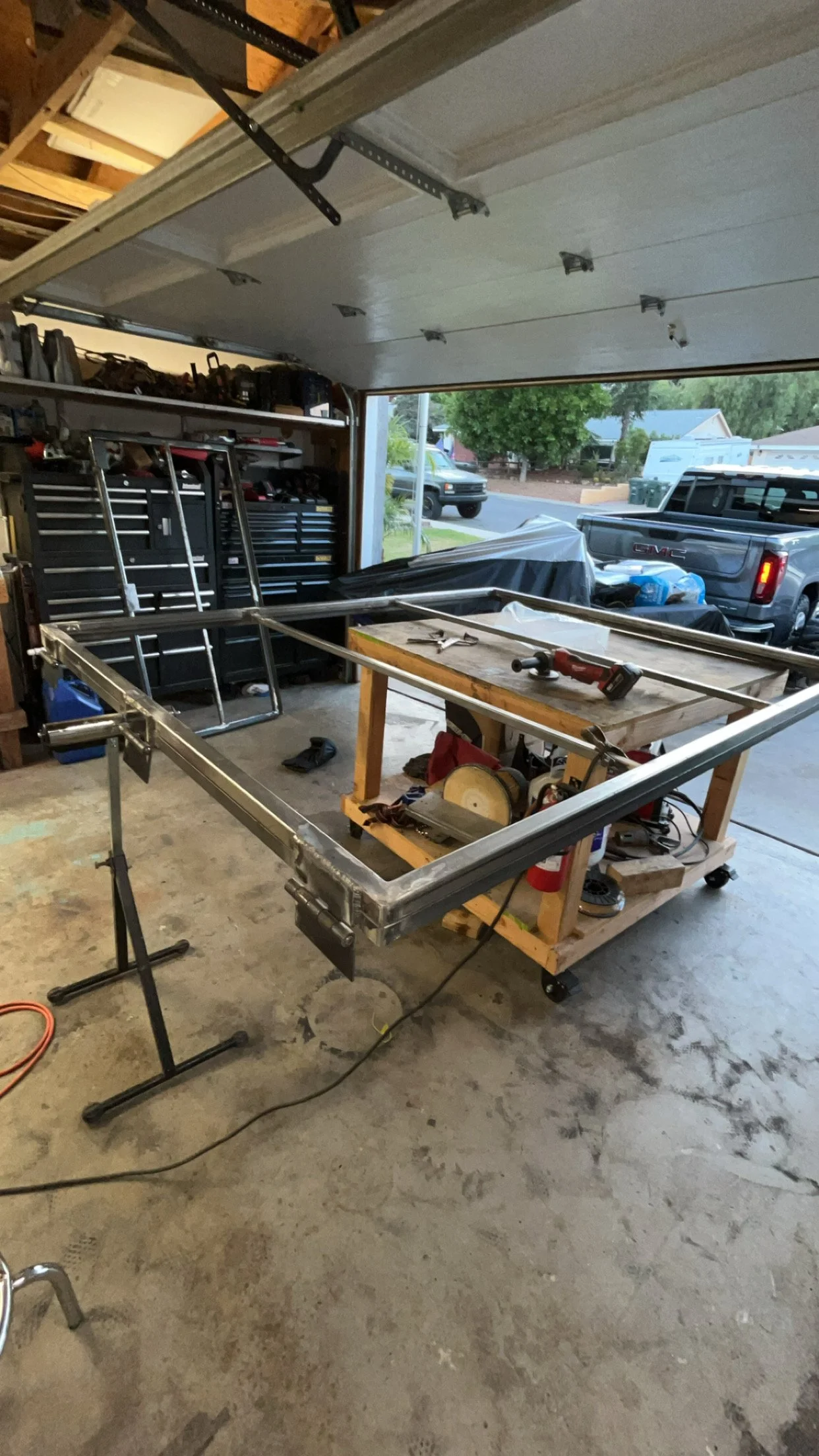Inside a garage workshop with metal frames, tools, and equipment for building or repairing a project.