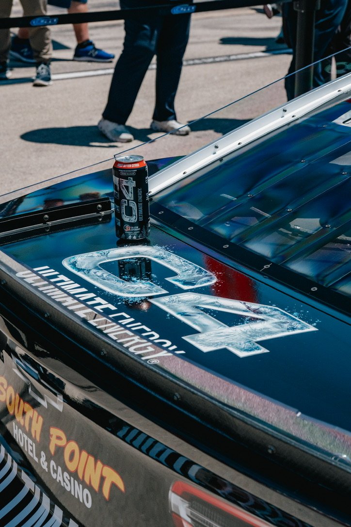 Close-up of racing car with a coca-cola can placed on top, with spectators visible in the background.
