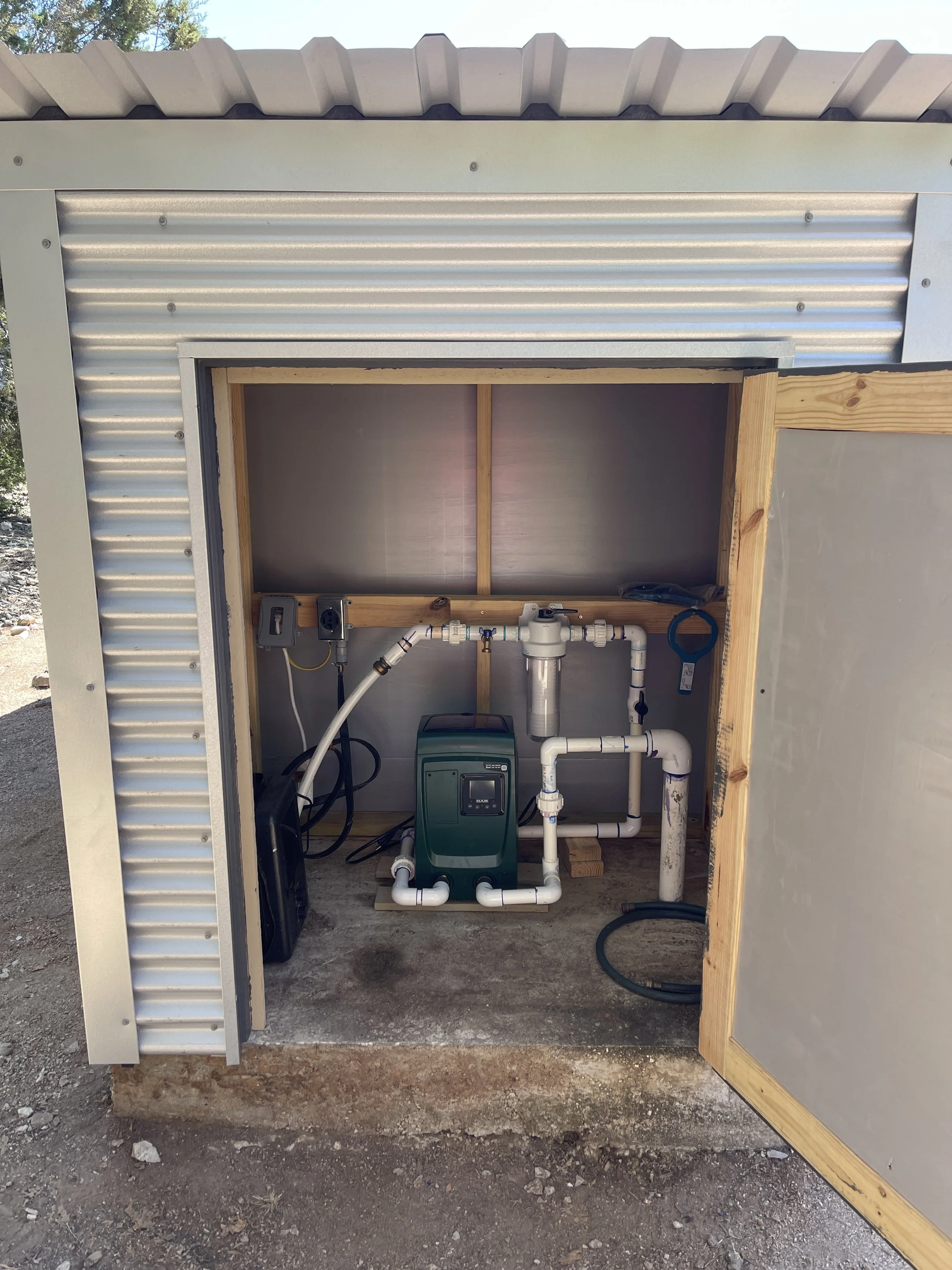 Turnkey rainwater pump and triple-filtration system with UV sterilization housed in a custom weather-protected enclosure, installed by Reinewater Solutions in Burnet Co.