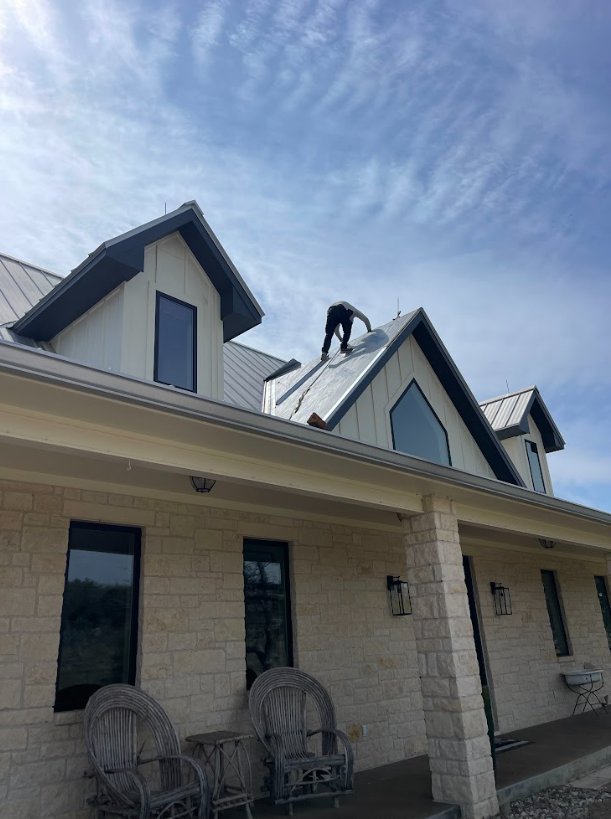 Custom standing seam metal roof and seamless aluminum gutters with round downpipes for rainwater collection, installed by Reinewater Solutions in Burnet Co.