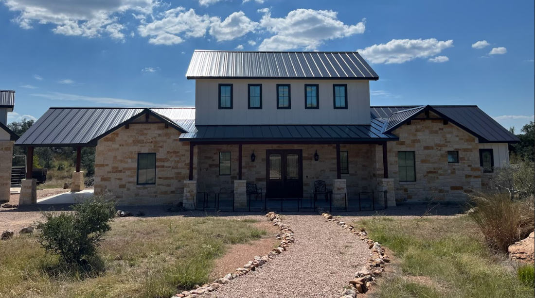Modern residential home with a charcoal gray standing seam metal roof designed for potable rainwater collection, installed by Reinewater Solutions.