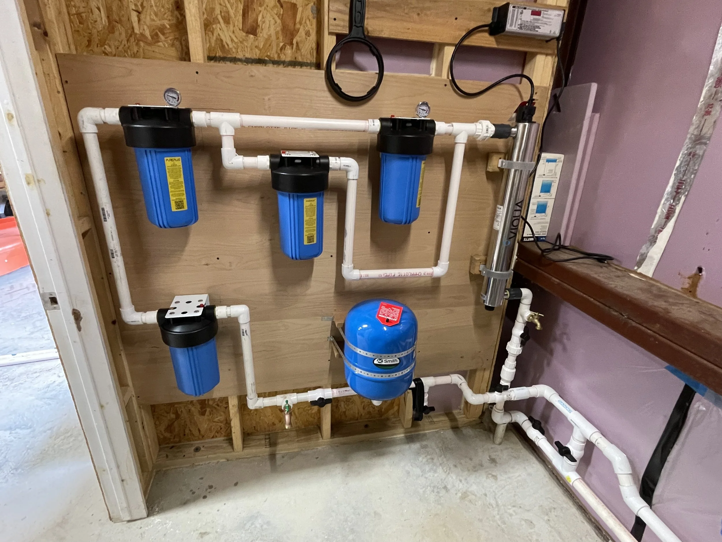 Wall-mounted triple-filtration system with UV sterilization for rainwater harvesting, professionally installed by Reinewater Solutions in Round Mountain, Texas.