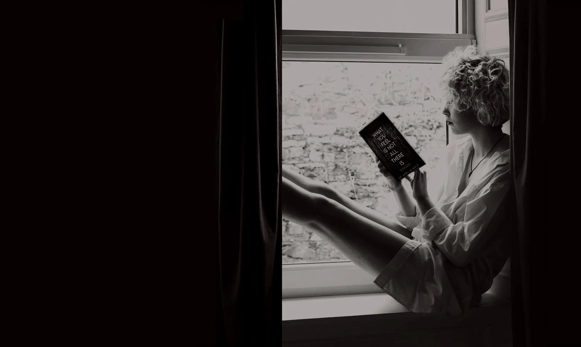 A woman with curly hair sitting by a window, reading a book titled "What you feel is not all there is" in black and white.