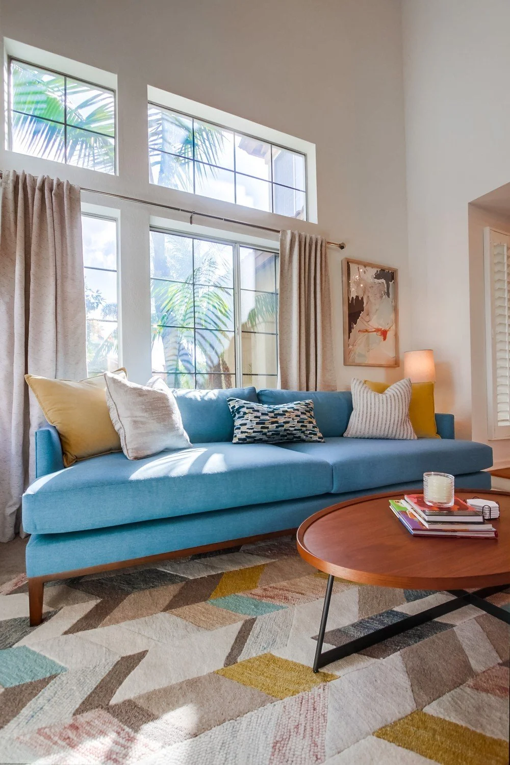 living room design with custom blue sofa, wood coffee table, geometric wool rug and natural light in San Diego home