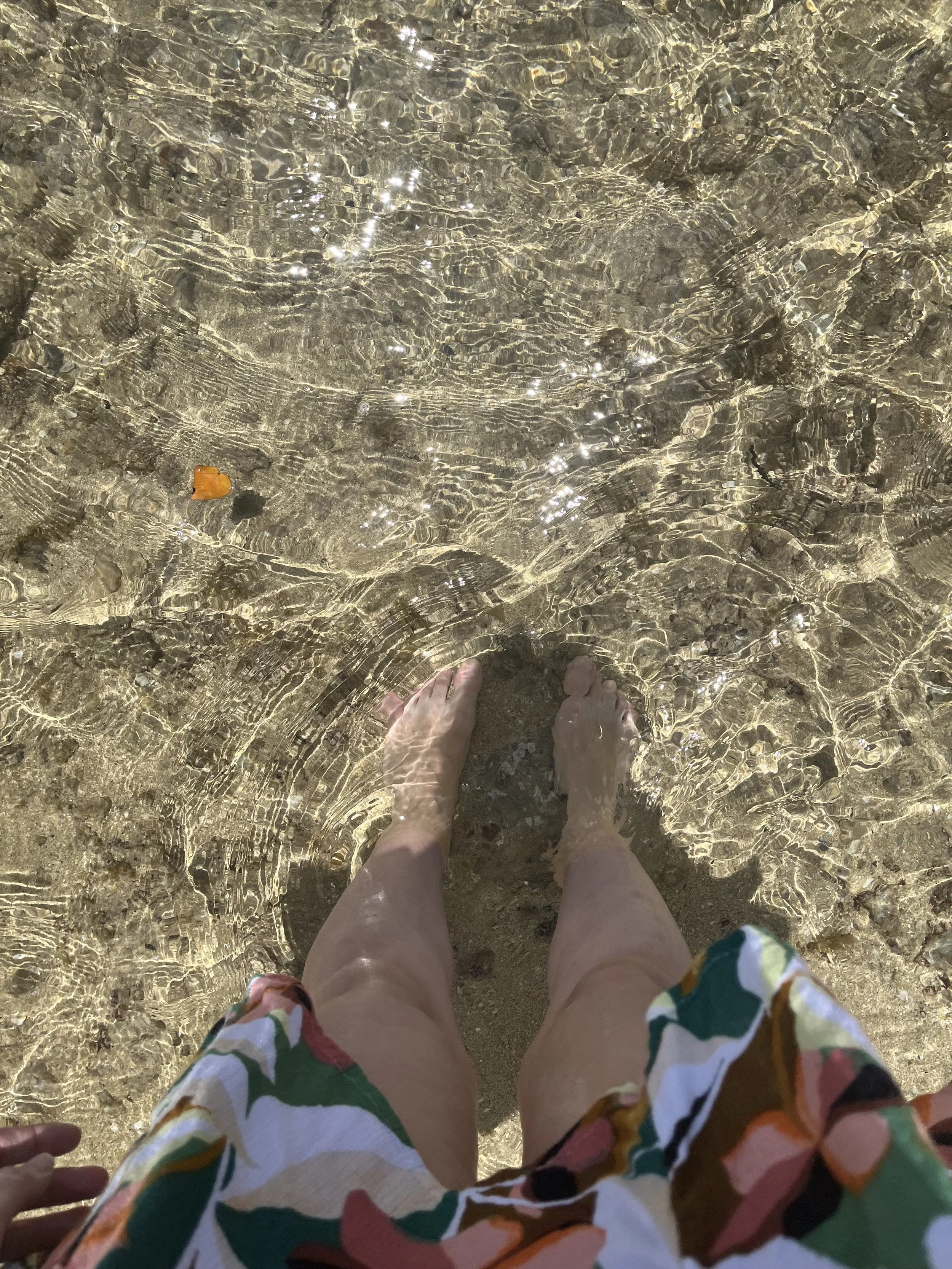 woman dipping feet into the ocean at the Kahala Resort beach area