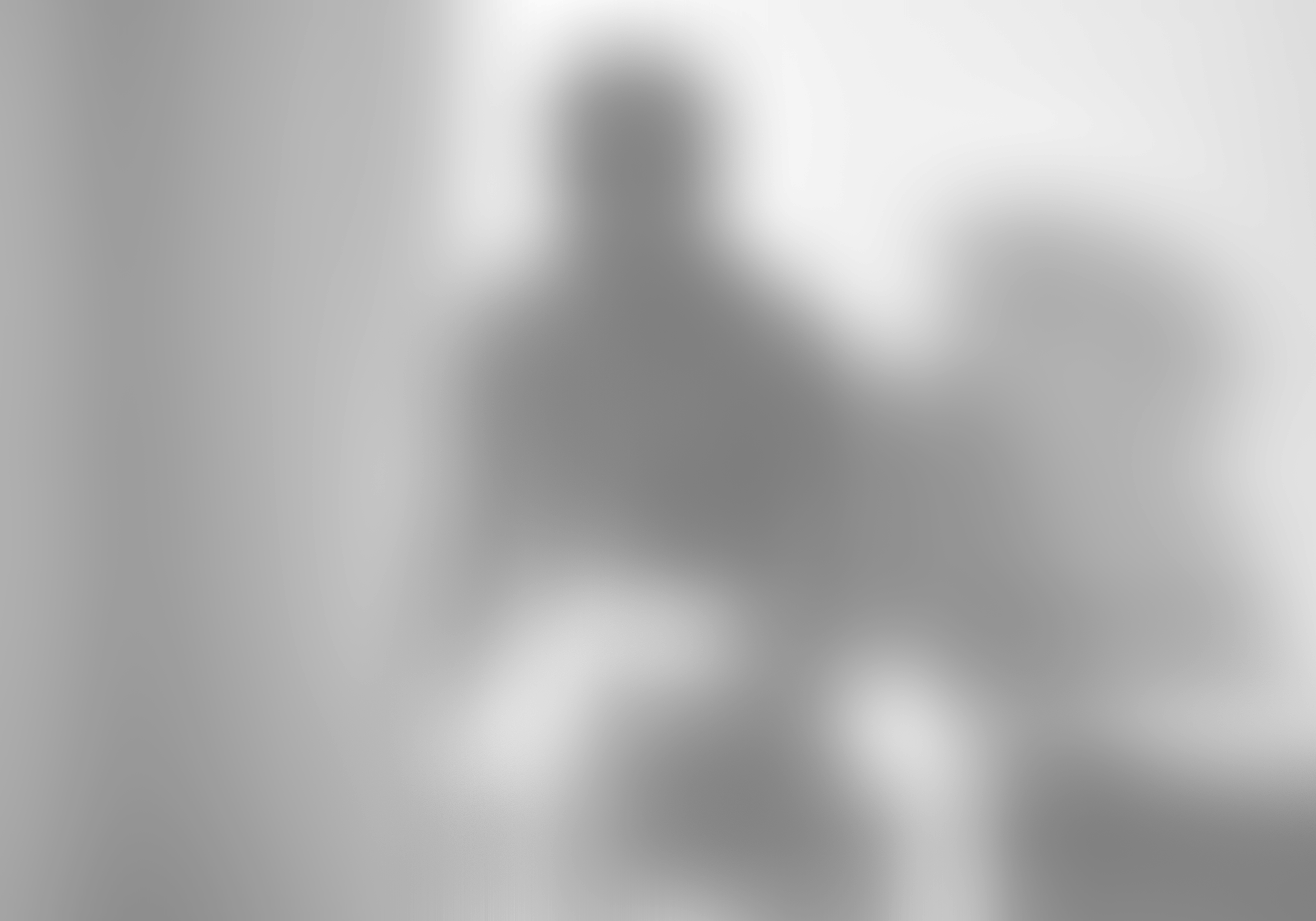 A human figure, with arms raised, standing on a skateboard in a room with wall and door in the background.