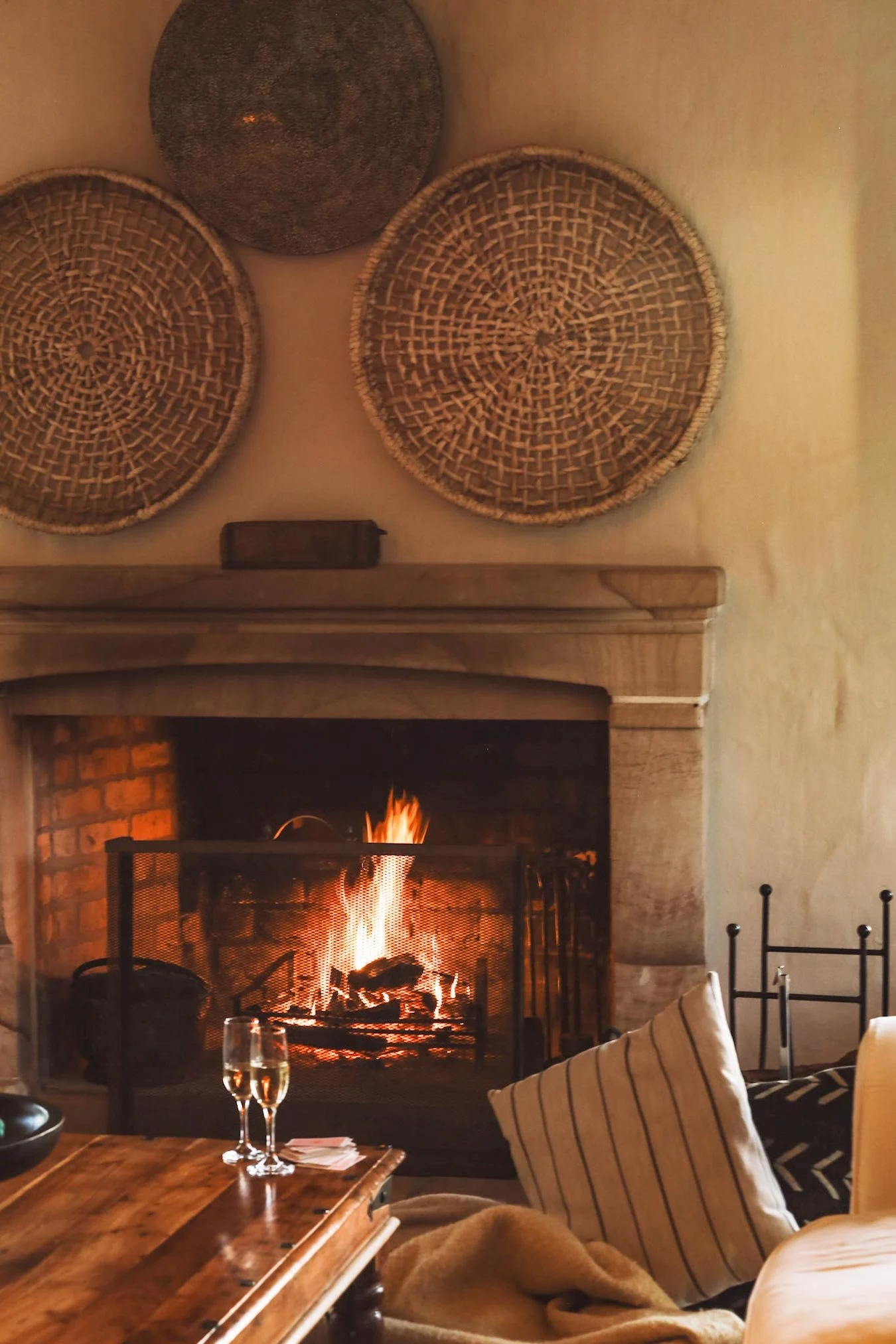 Living room with fireplace, wicker wall decorations, and a cozy atmosphere. Private luxury villa (accommodation) in Hemel-en-Aarde, Hermanus.