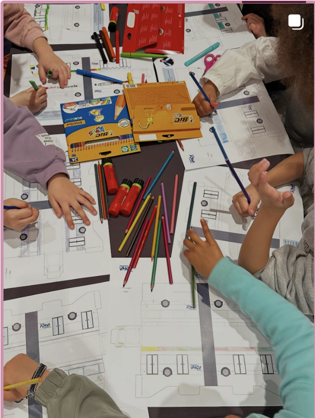 Enfants en train de dessiner et de colorier sur des plans ou des schémas avec des crayons et des feutres, autour d'une table.