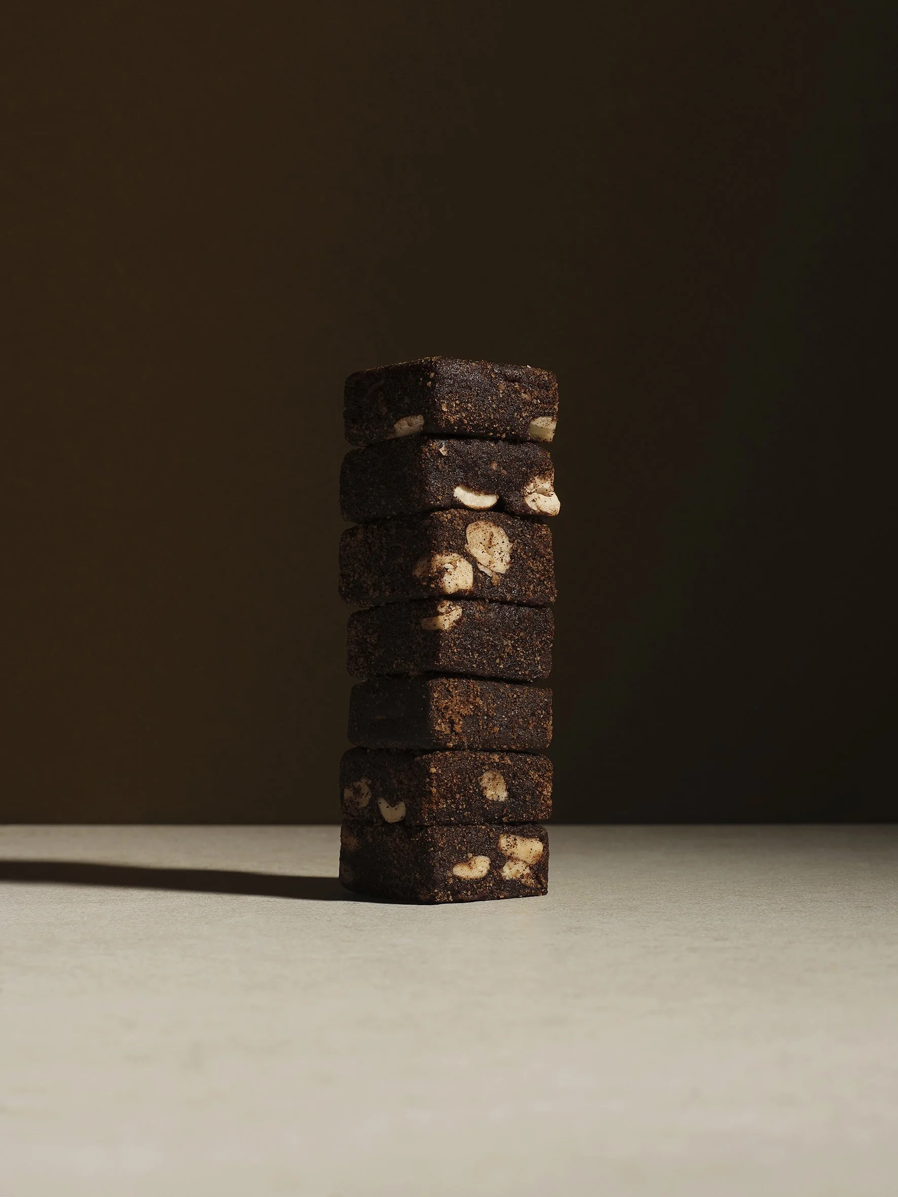 Stack of chocolate before and after cookies with white nuts on a beige surface and brown background.