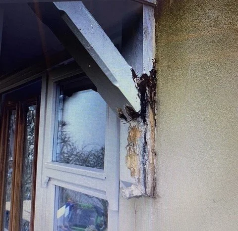 Damaged exterior wall with black soot and corrosion around a window