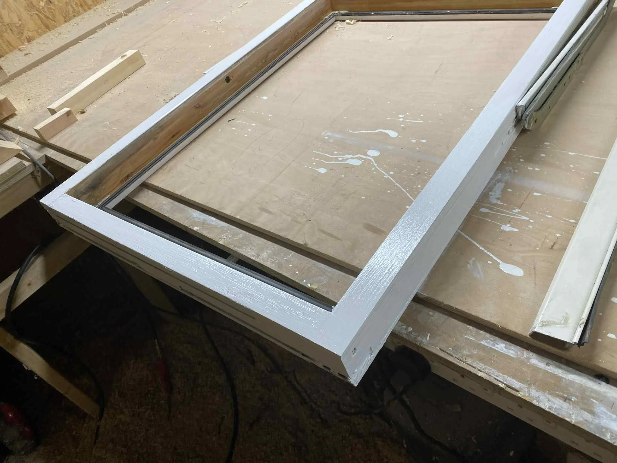 Wooden frame with metal sliding tracks on a workbench in a workshop.
