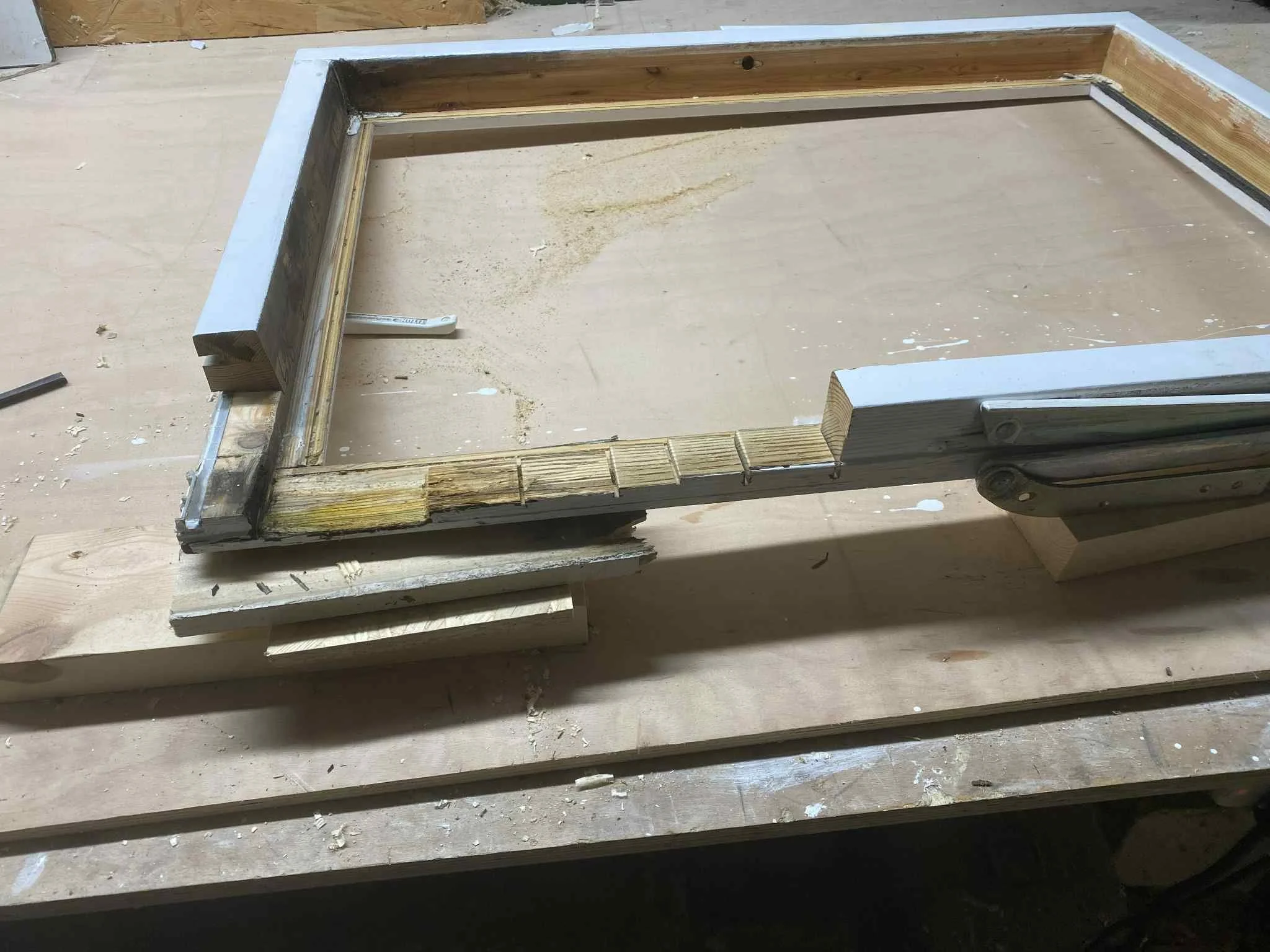 Wooden frame construction on a workbench, with parts of the frame connected and supported by wooden blocks, in a woodworking workshop.