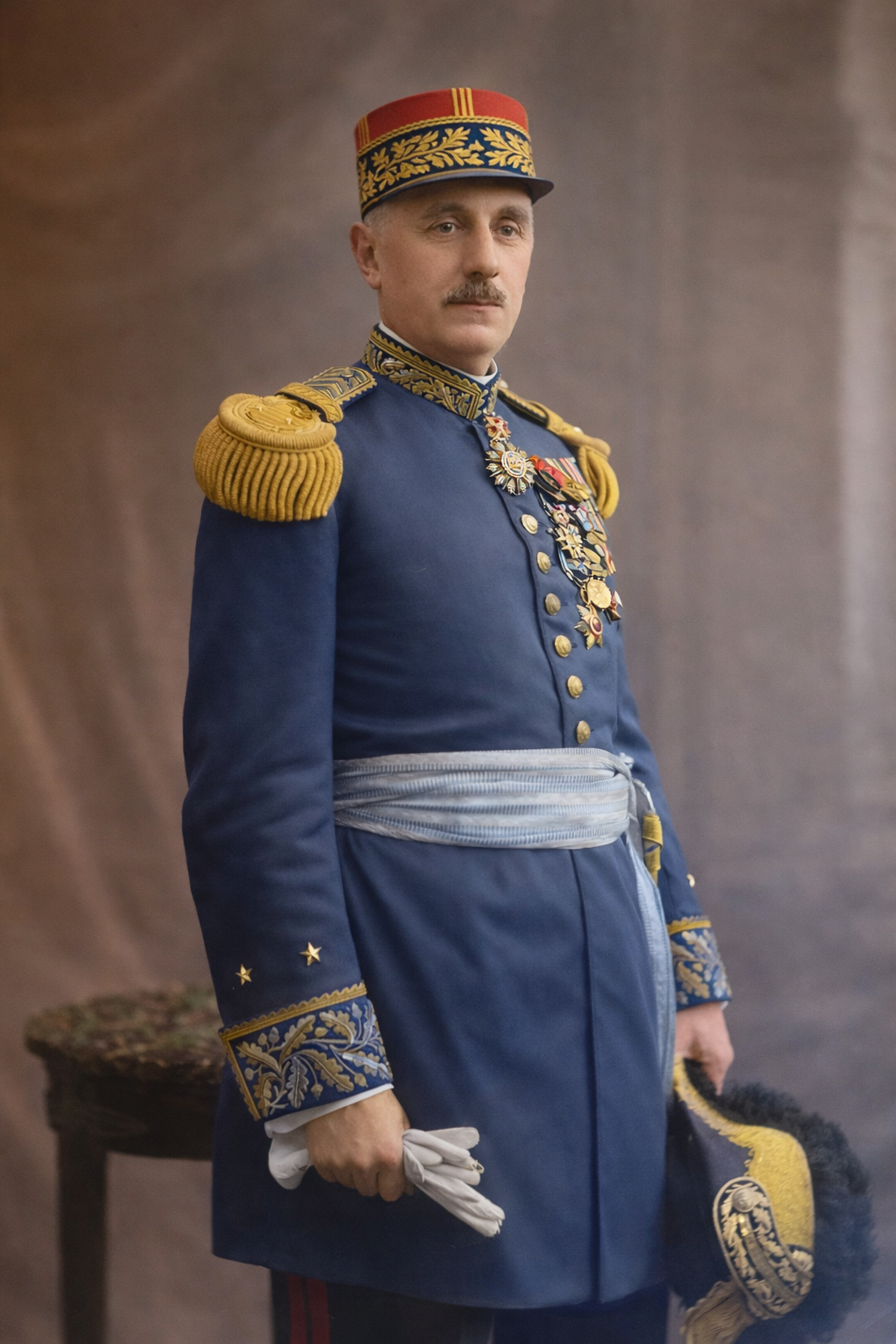Homme en uniforme militaire français avec des médailles et un chapeau en accueil officiel.