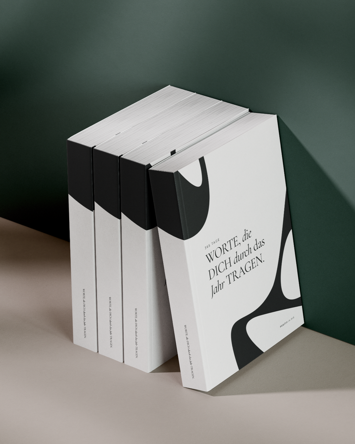 Vier Bücher mit schwarzem und weißem Cover, das eine abstrakte Design und den Titel '365 Tage Worte, die dich durch das Jahr tragen' zeigt, stehen gegen eine grüne Wand.