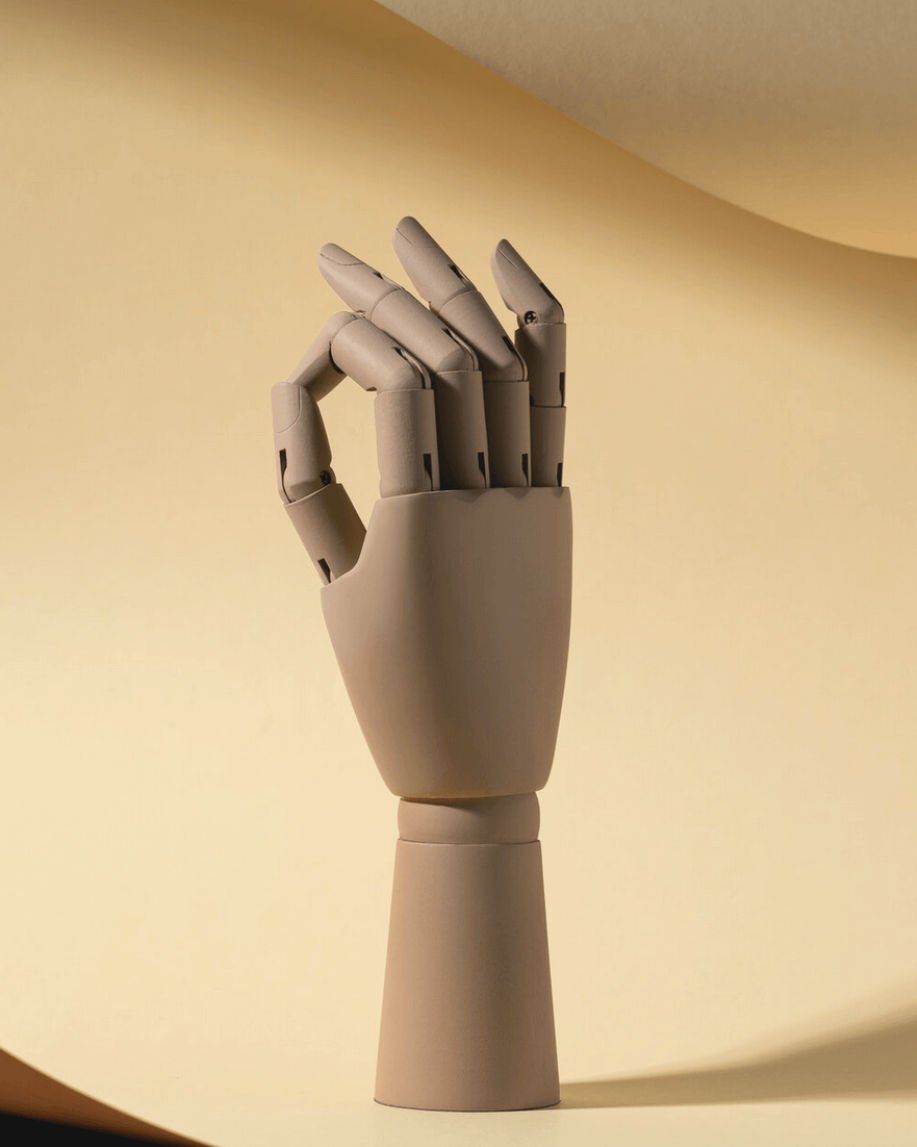 A beige wooden hand with fingers slightly curled, positioned upright, against a plain yellow background.