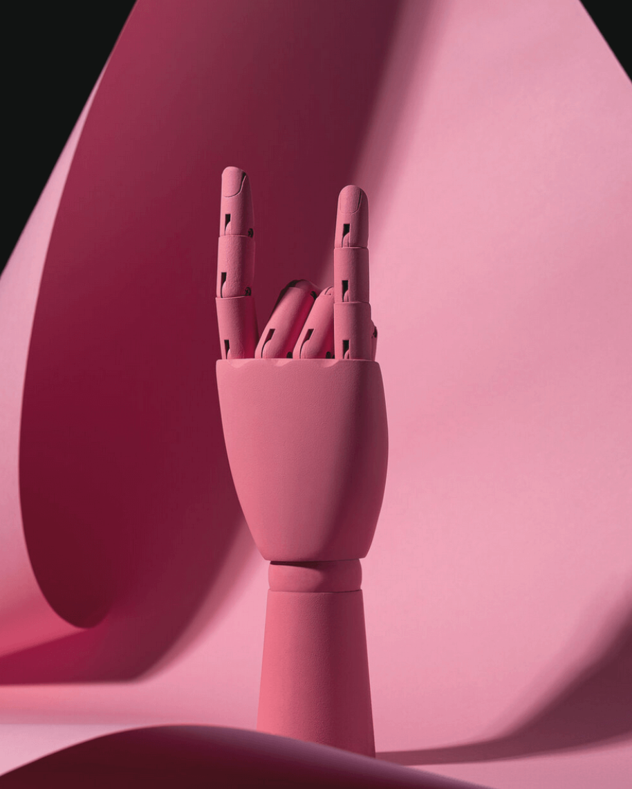 A pink wooden hand making the peace sign against a pink textured background.