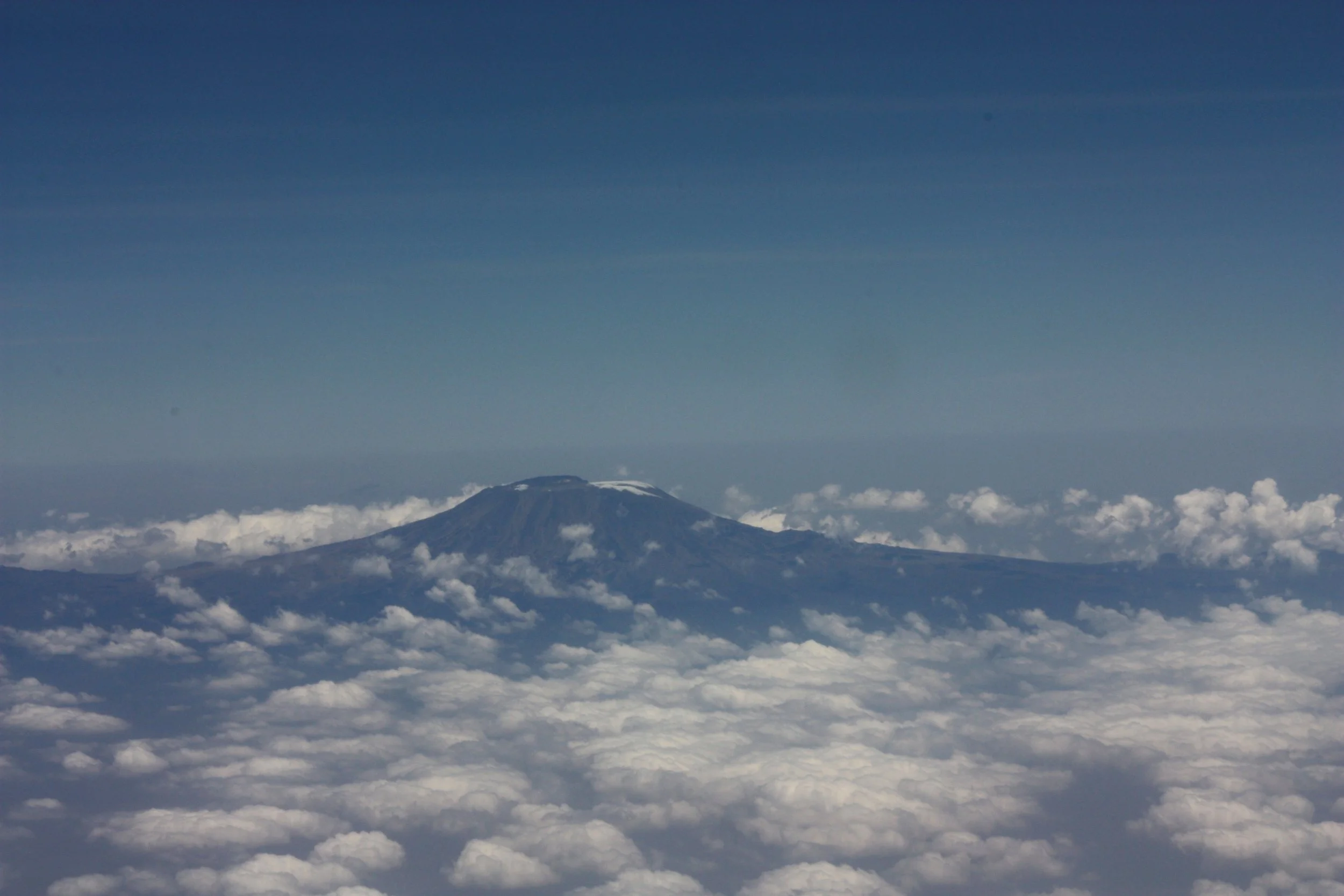Uitzicht op een vulkaan boven de wolken met een heldere blauwe lucht