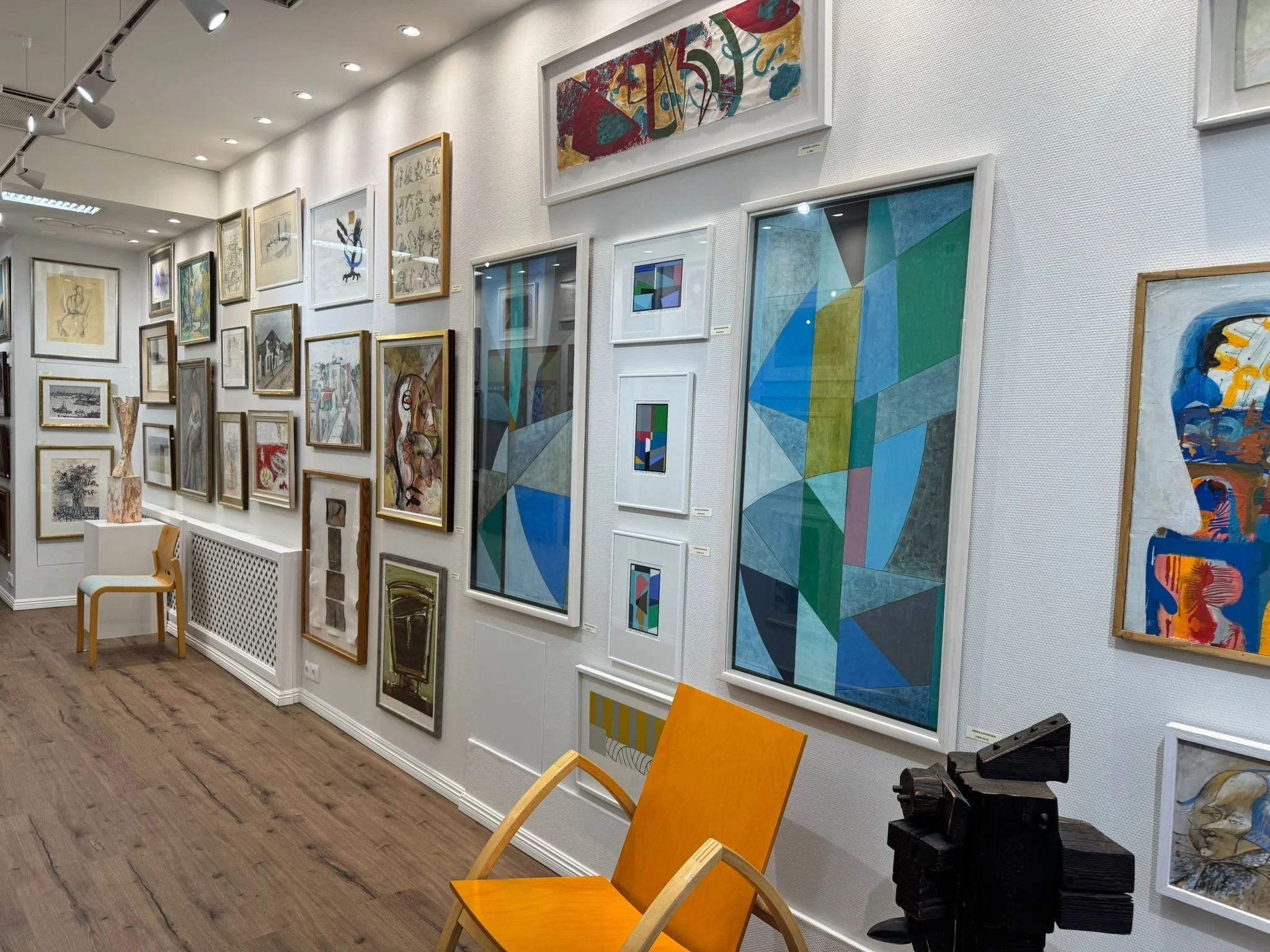 Kuvassa on taidegalleria, jossa seinällä on monenlaisia taideteoksia, kuten maalauksia, piirustuksia ja grafiikoita, ja huoneessa on myös veistoksia.