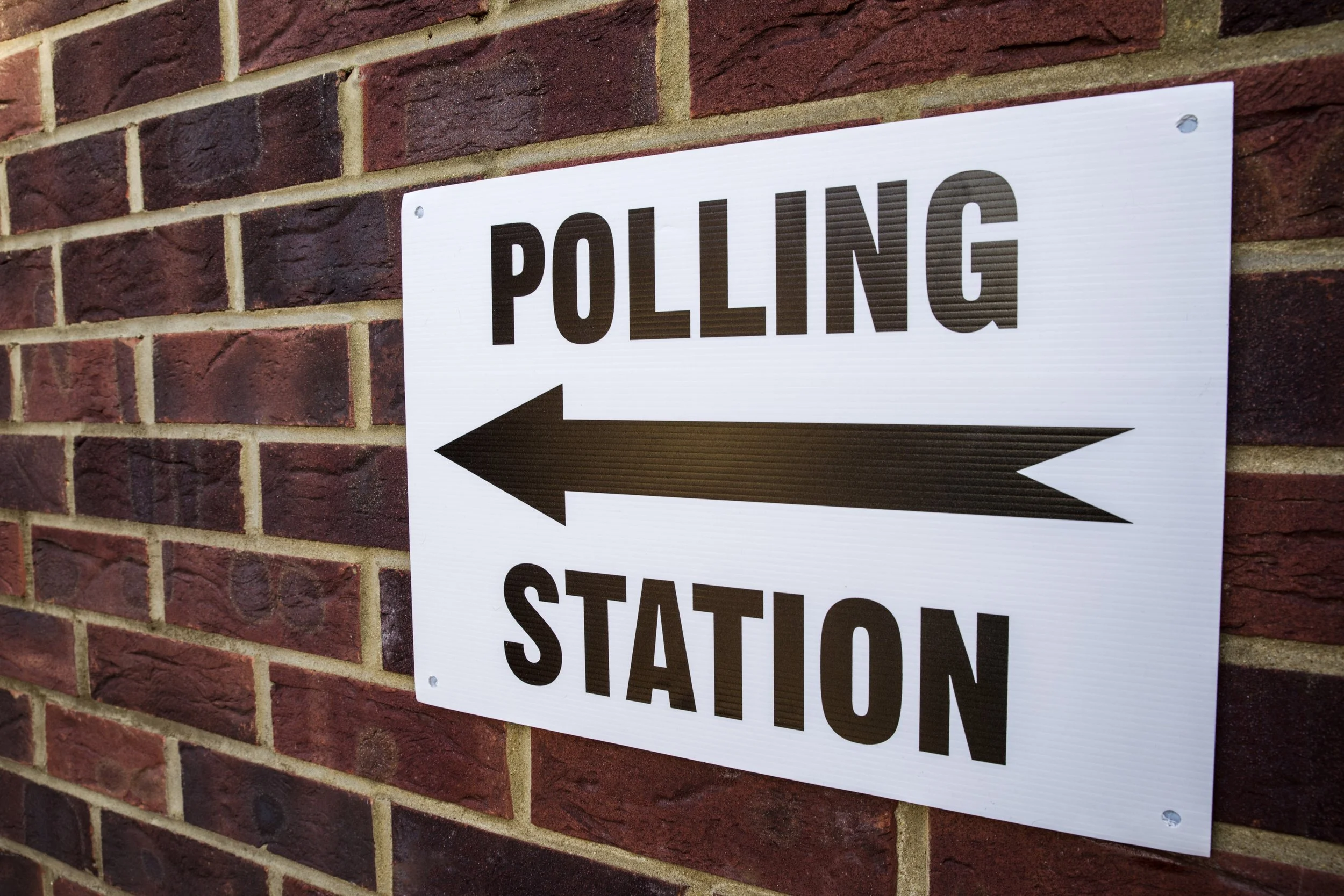 Sign on a brick wall directing voters to a UK polling station, symbolising debates over electoral reform and Proportional Representation at the Liberal Democrat conference