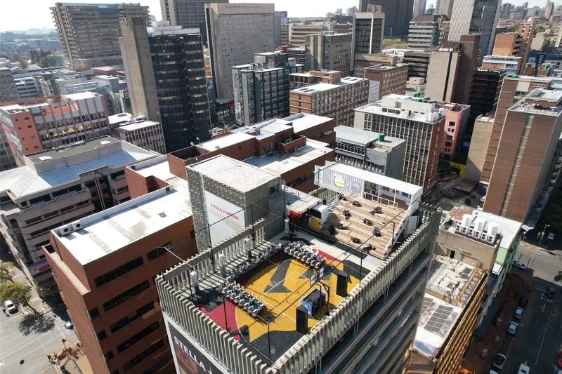 A rooftop basketball court on top of a high-rise building in an urban area, surrounded by numerous skyscrapers.