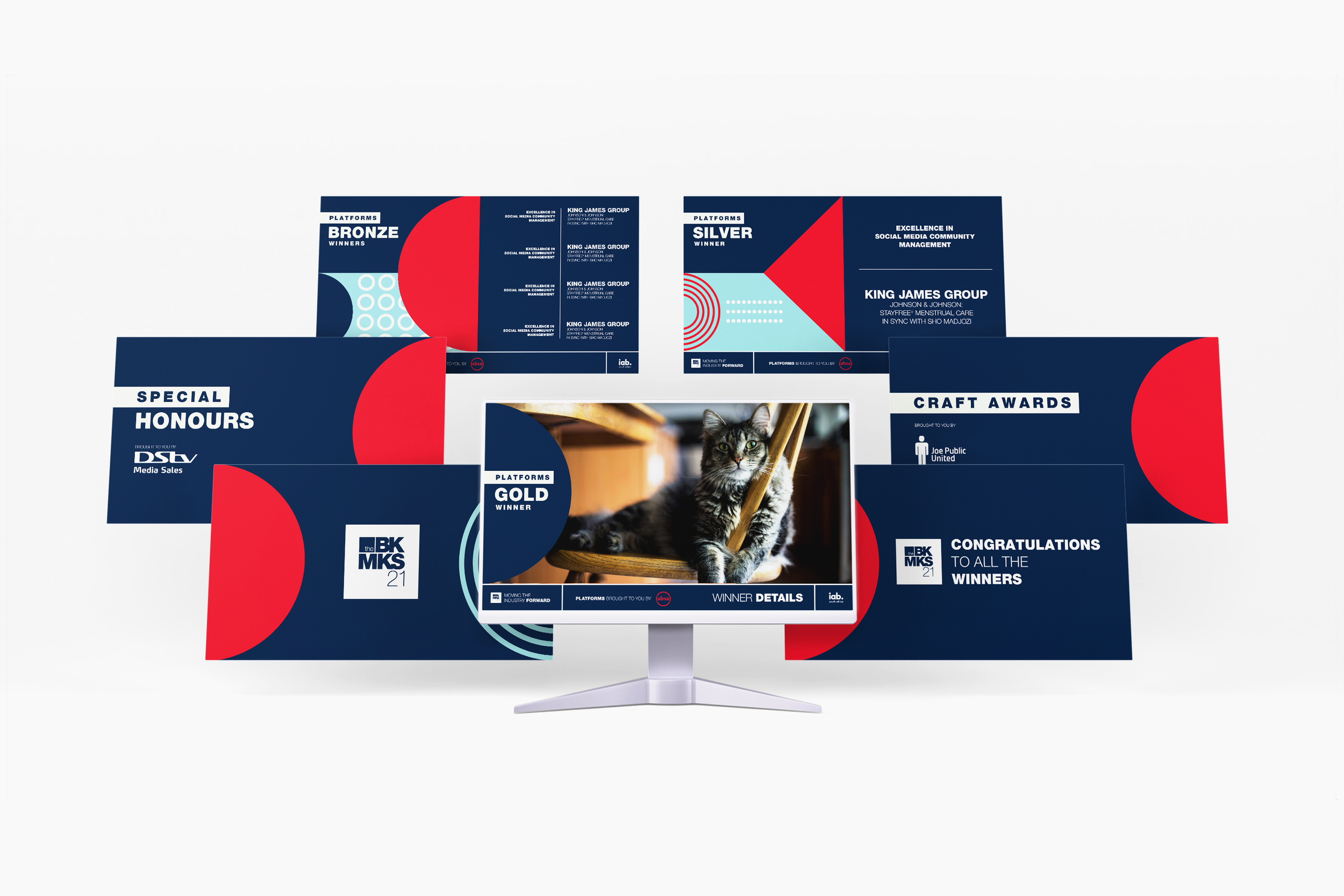 A computer monitor displaying a photo of a domestic cat resting on a staircase, surrounded by various digital award graphics for a corporate event, with a predominantly navy blue, red, and white color scheme.