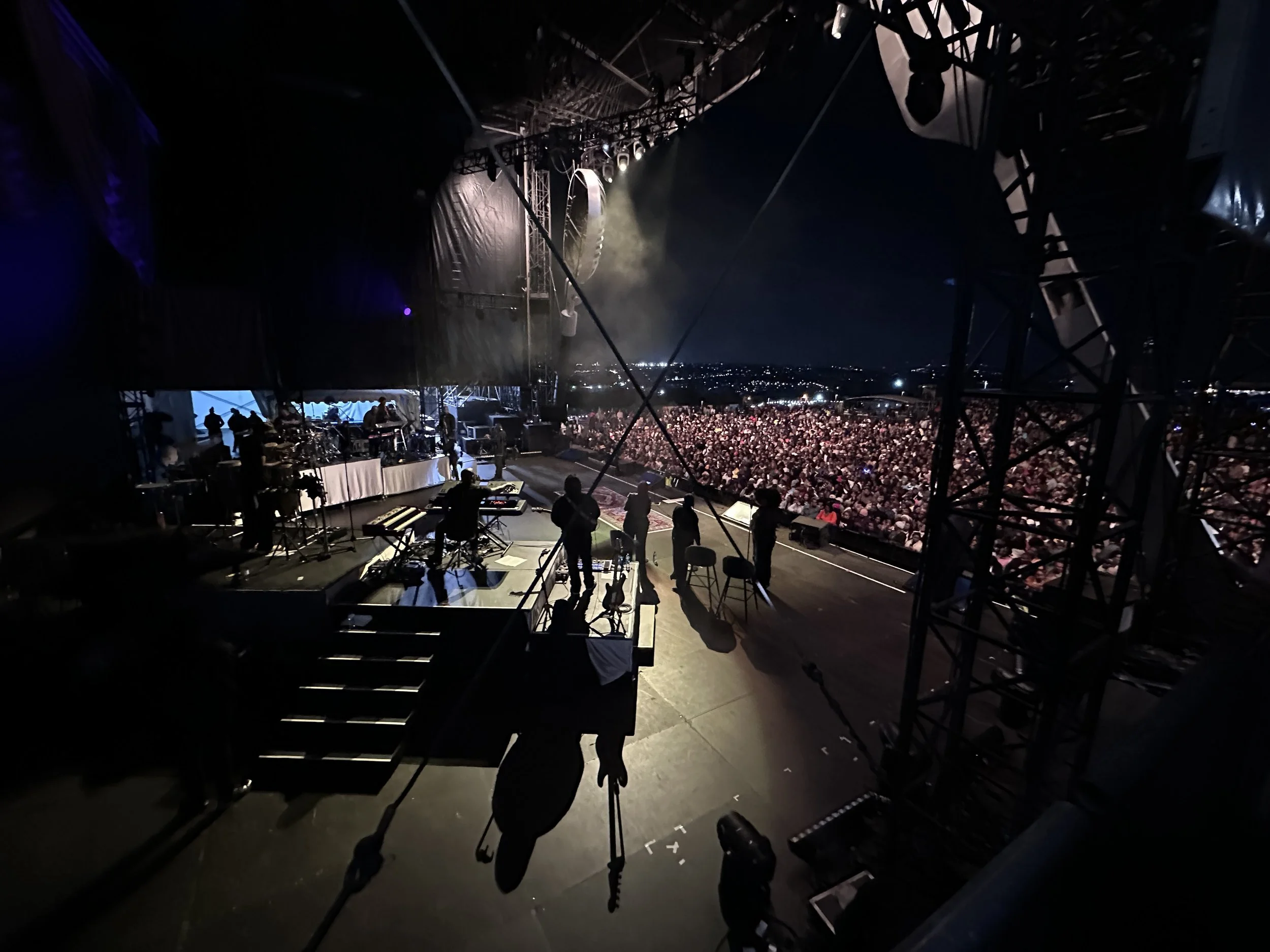 View from the stage showing musicians setting up with an audience outside at night.