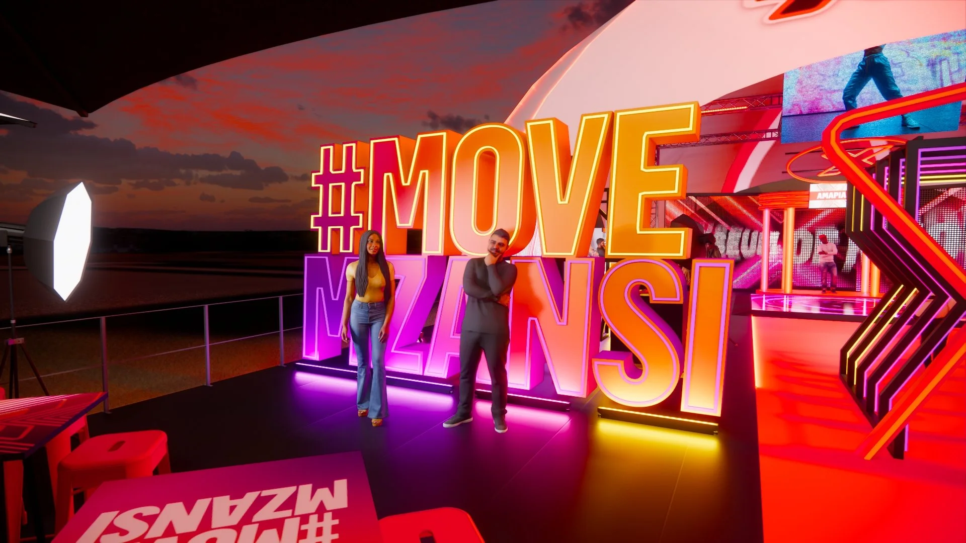 Two people standing in front of large, illuminated hashtag and text signs that say '#MOVEZINSI' on a colorful, neon-lit stage with a sunset sky in the background.
