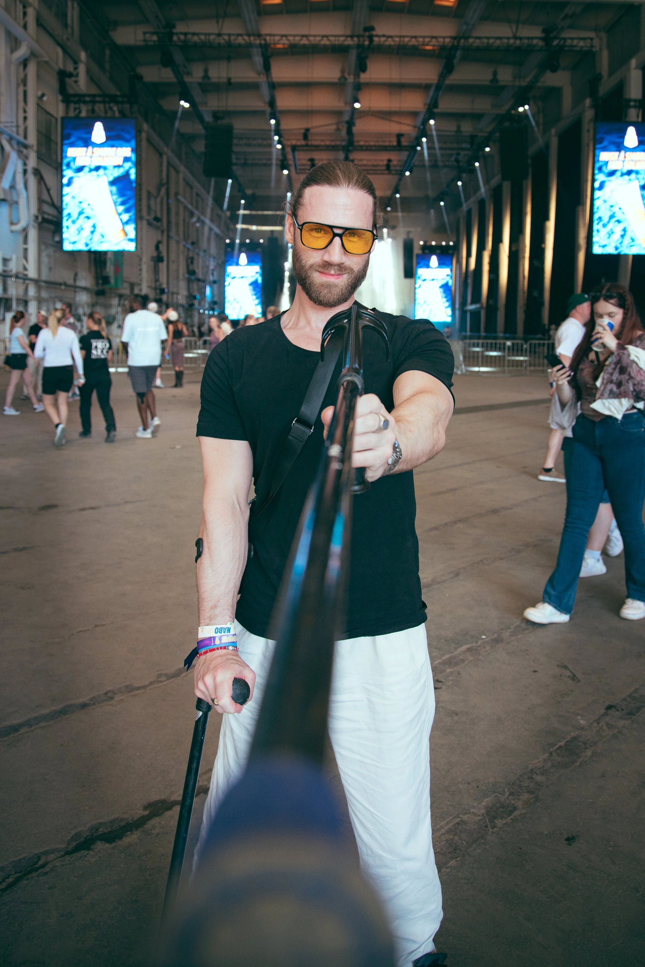 En mann gjør en selfie med en gimbal-stabilisator på en innendørs konsert eller festival.