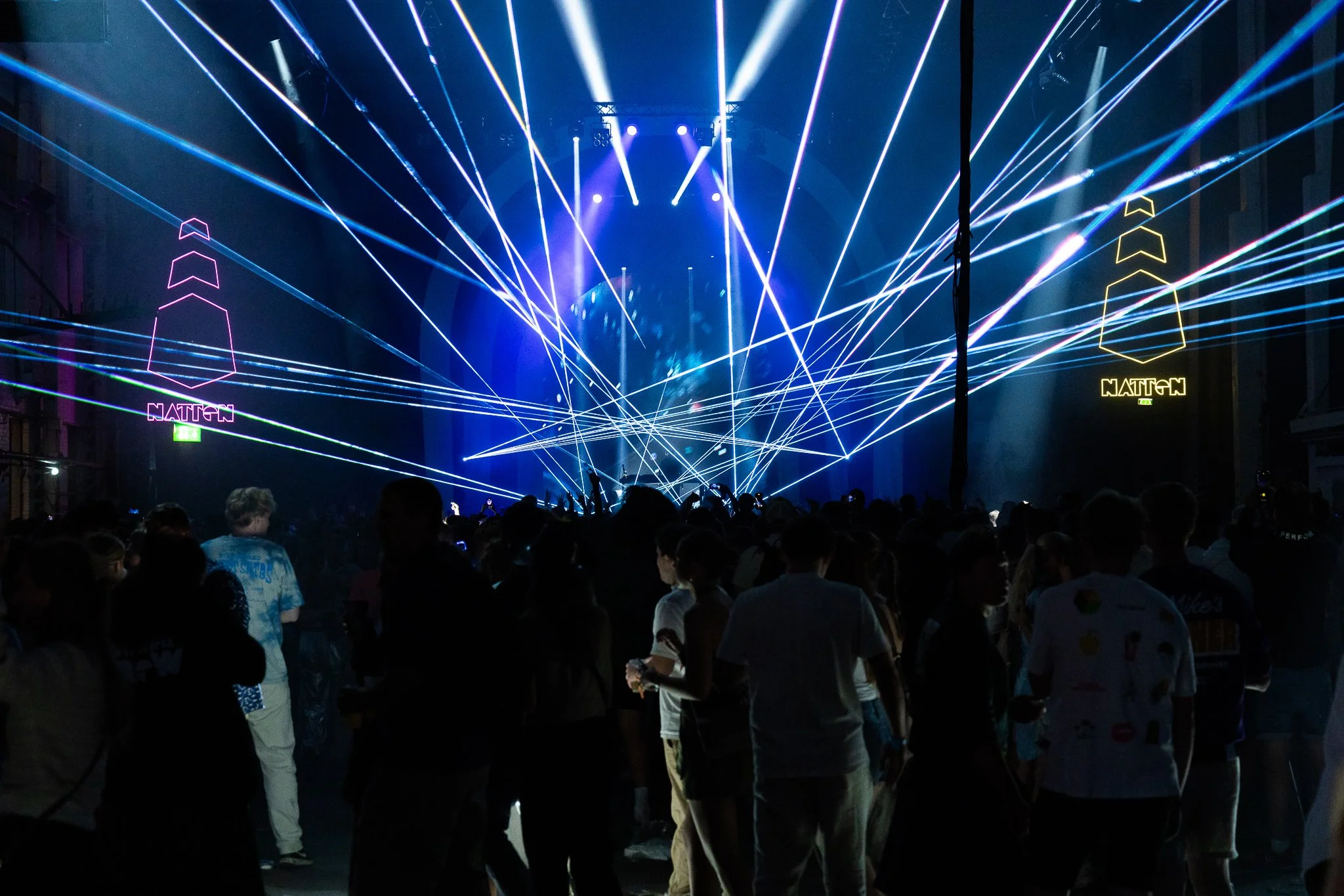 En stor folkemengde foran en scene med lysshow og laserlys, nattid. Slottsfjell natten 2023