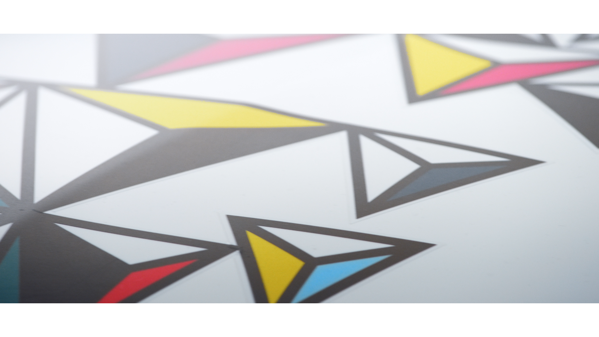 Close-up of a geometric paper art design with interconnected triangles in black, white, yellow, red, and blue colors.