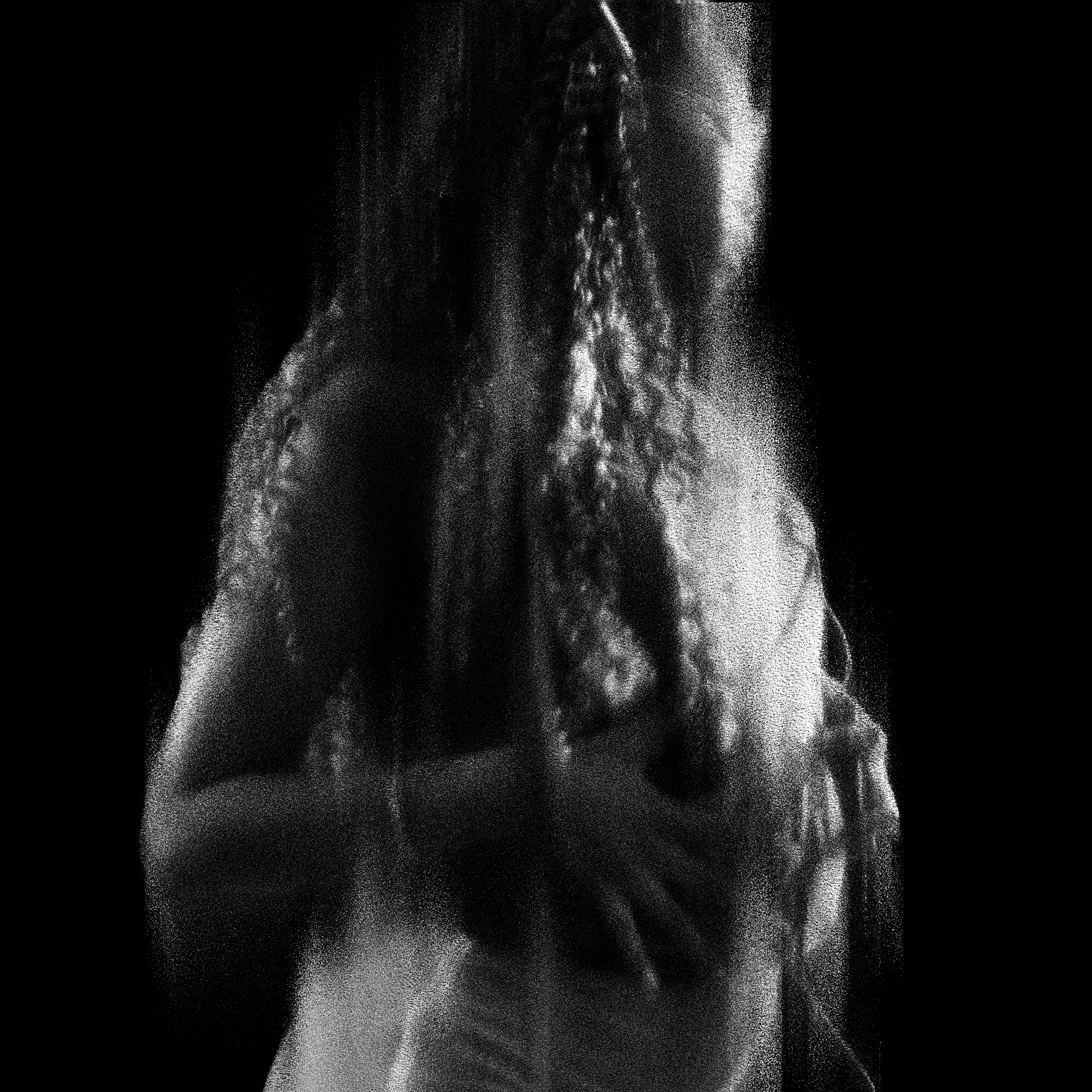 A woman with curly hair in a hoodie, looking down with her hand on her face, in a black and white photo.