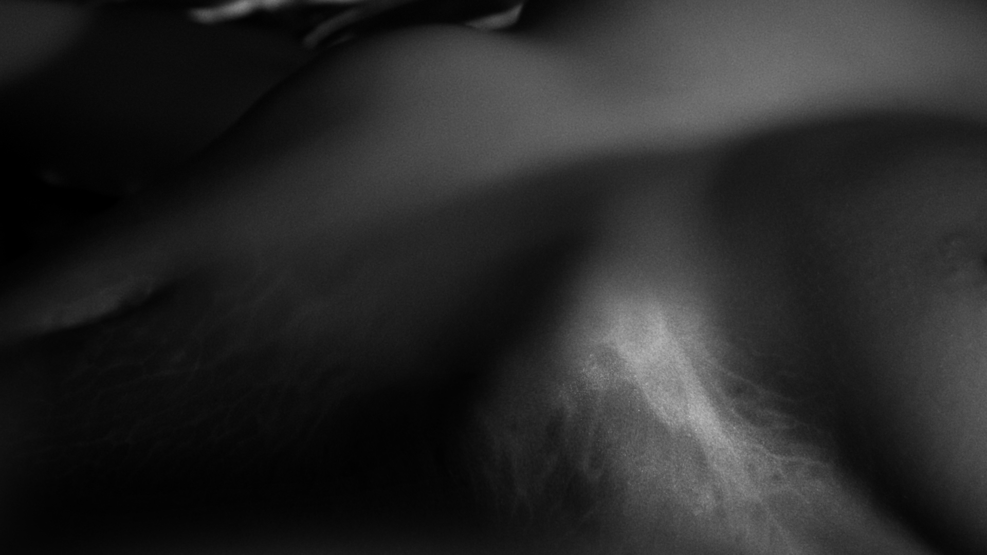 Close-up black and white image of a human face, blurred and abstract.