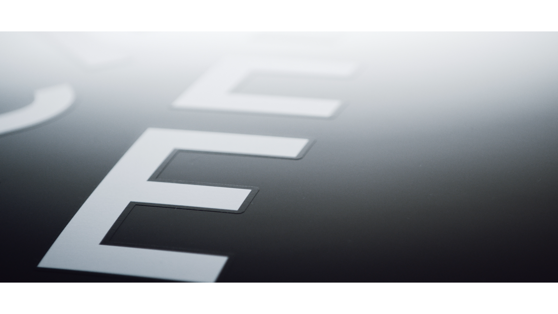 Close-up of metallic letters spelling 'ELI' on a dark reflective surface.