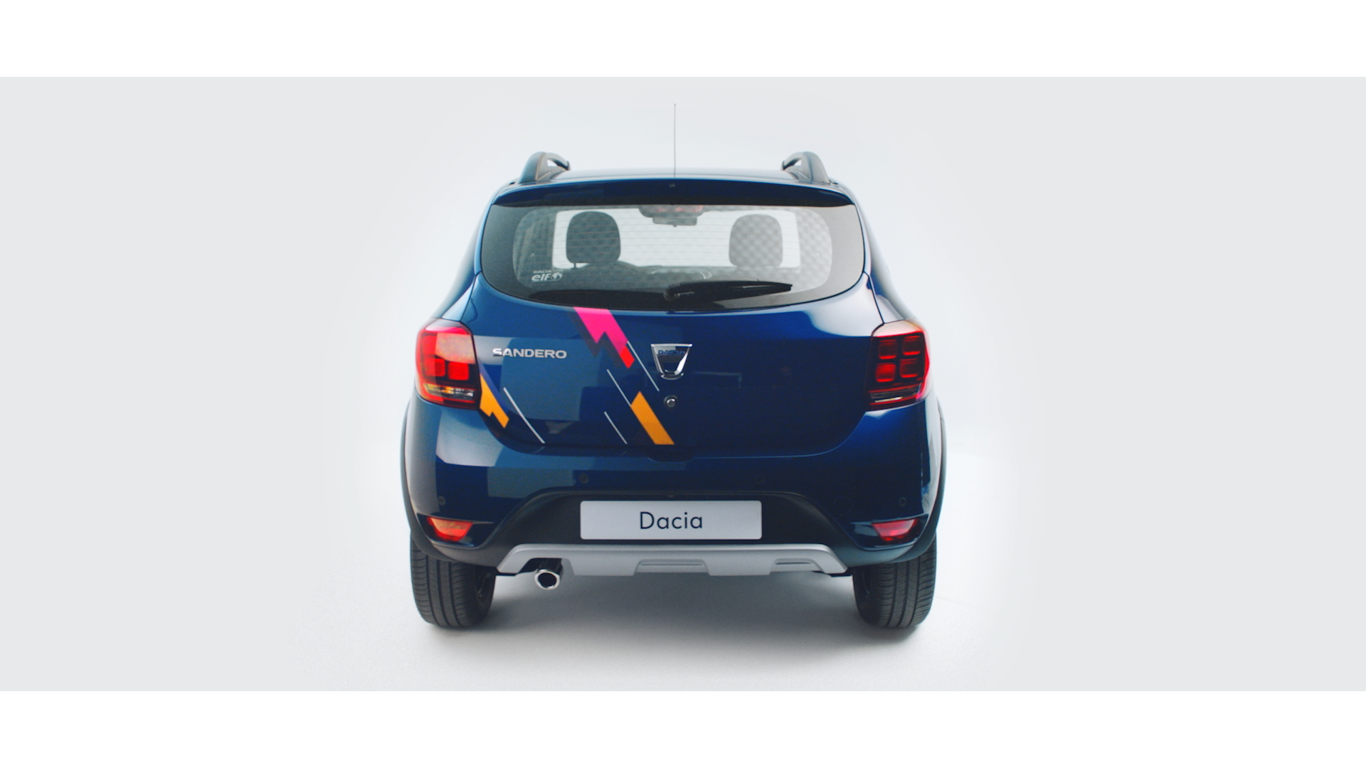 Rear view of a blue Dacia Sandero car with colorful stripe decals, showing Dacia and Sandero badges, against a white background.