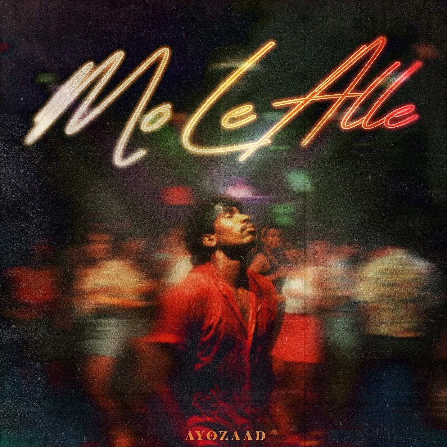 Neon sign reading 'McElle' above a young man in a red shirt looking upward in a dimly lit nightclub with blurred dancing people in the background.