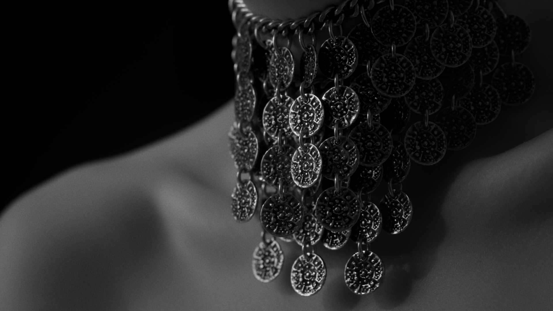 Close-up of hanging silver jewelry with intricate circular designs, captured in black and white