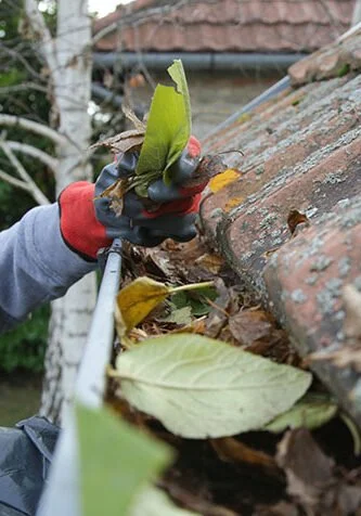Photo of a roofer cleaning a clogged gutter, illustrating similar Stork Roofing services in Aberdeen and Aberdeenshire