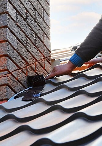 A worker on a roof installing chimney flashing as done by Stork roofing in Aberdeen during slating and tiling repair