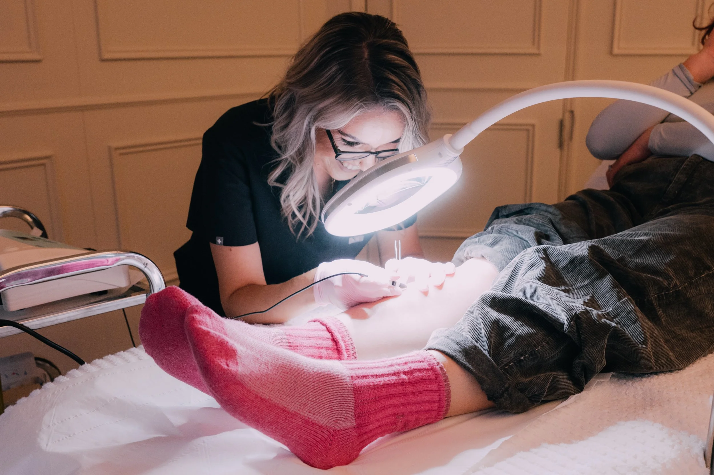 Dentist or dental hygienist examining or treating a patient's teeth under a bright light in a dental office.