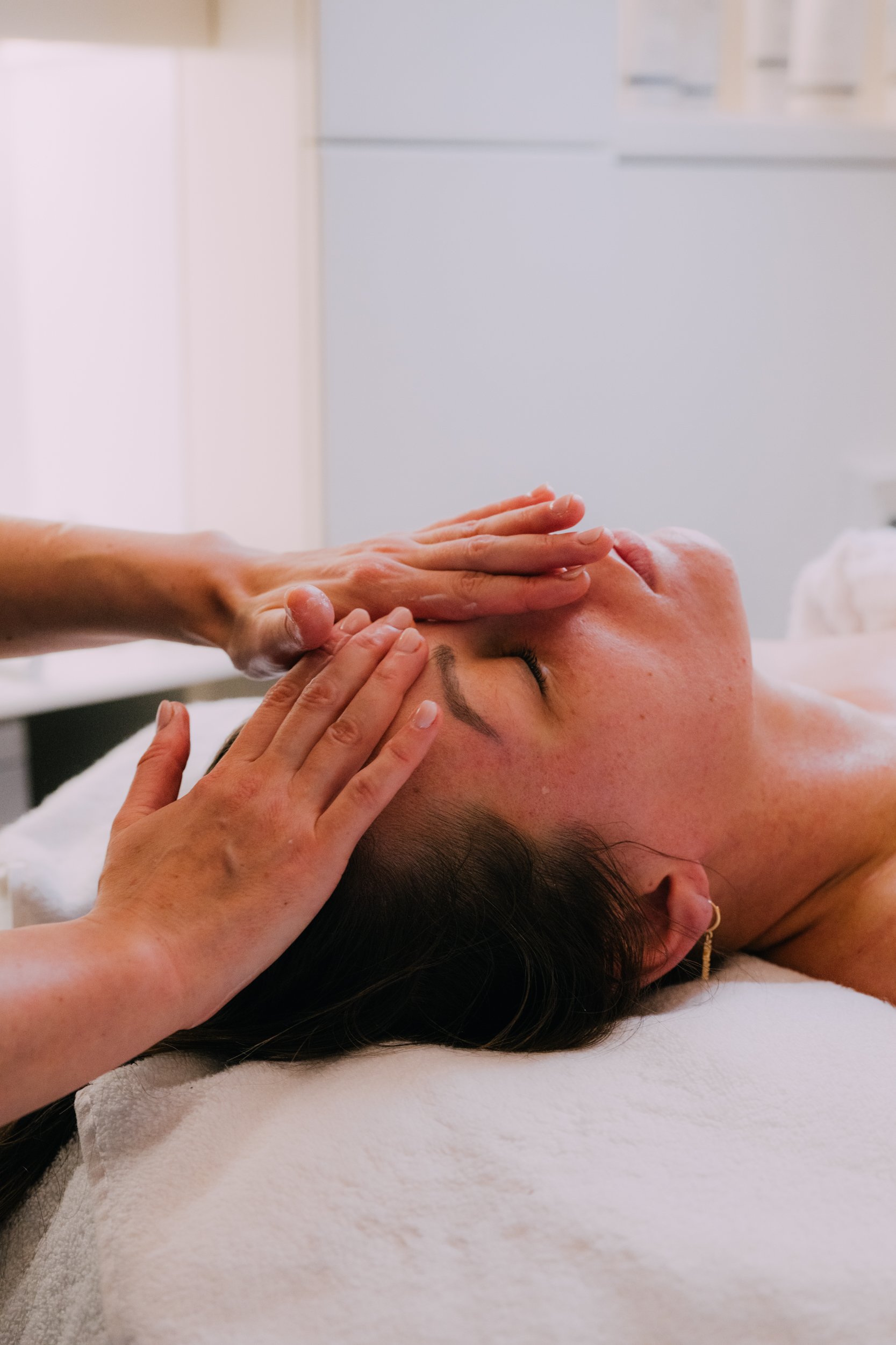 Person receiving a facial massage or skincare treatment in a spa or clinic setting.