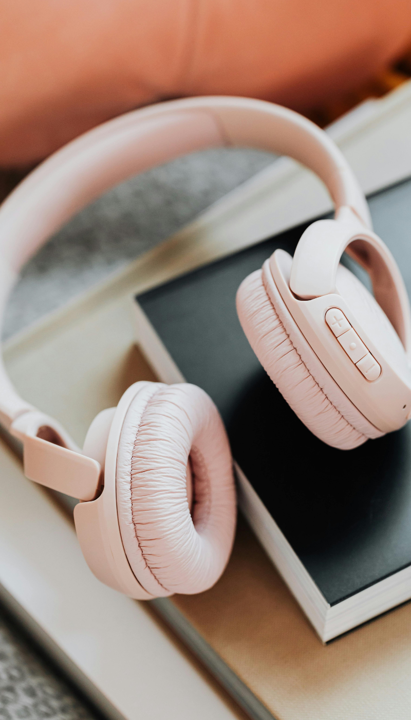 Pink over-ear headphones resting on a book for Lara Desrosiers' Pelvic Resilience for occupational therapy continuing education and mentorship.