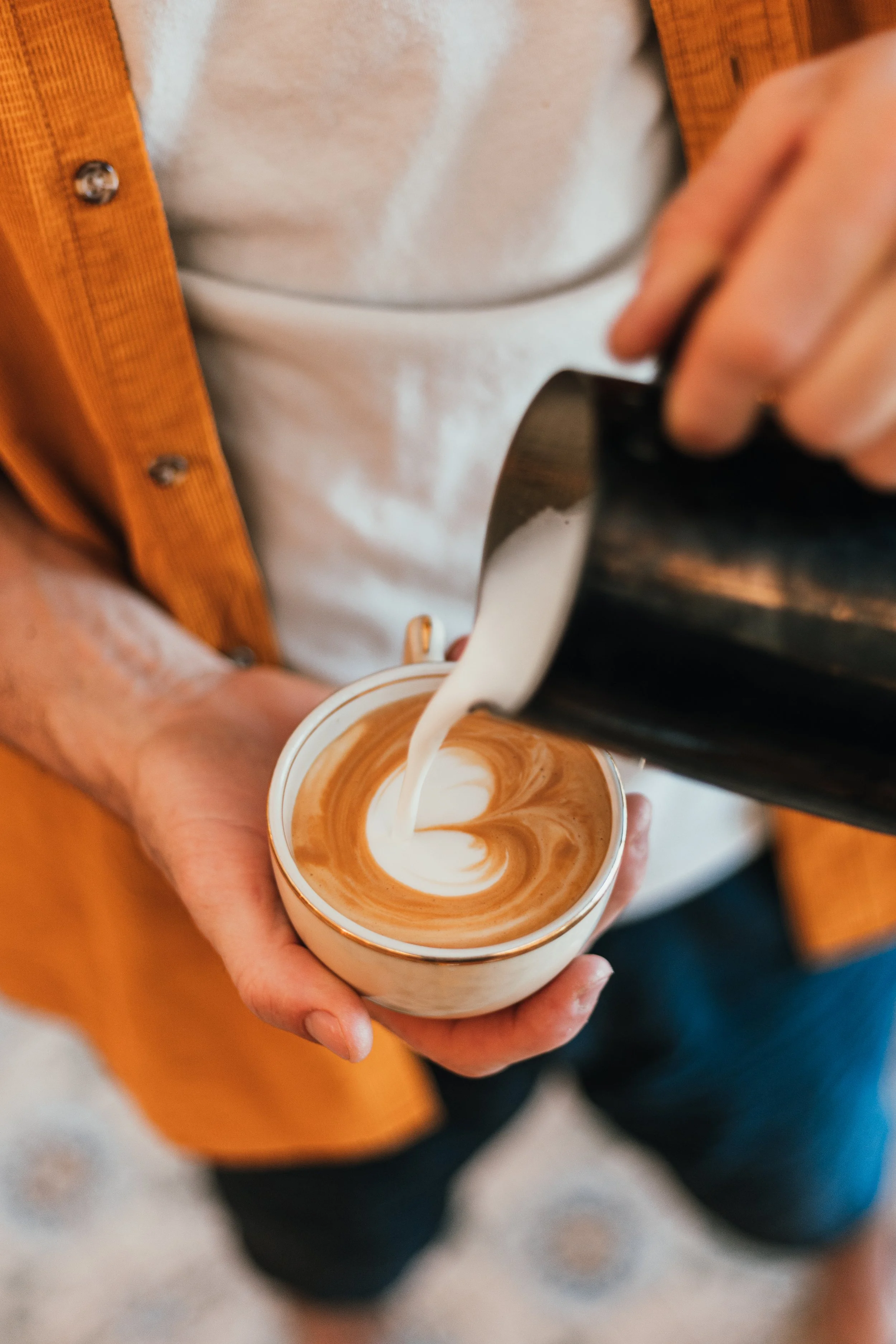 Une personne verse du lait chaud dans un café latte pour créer un motif de marbre.