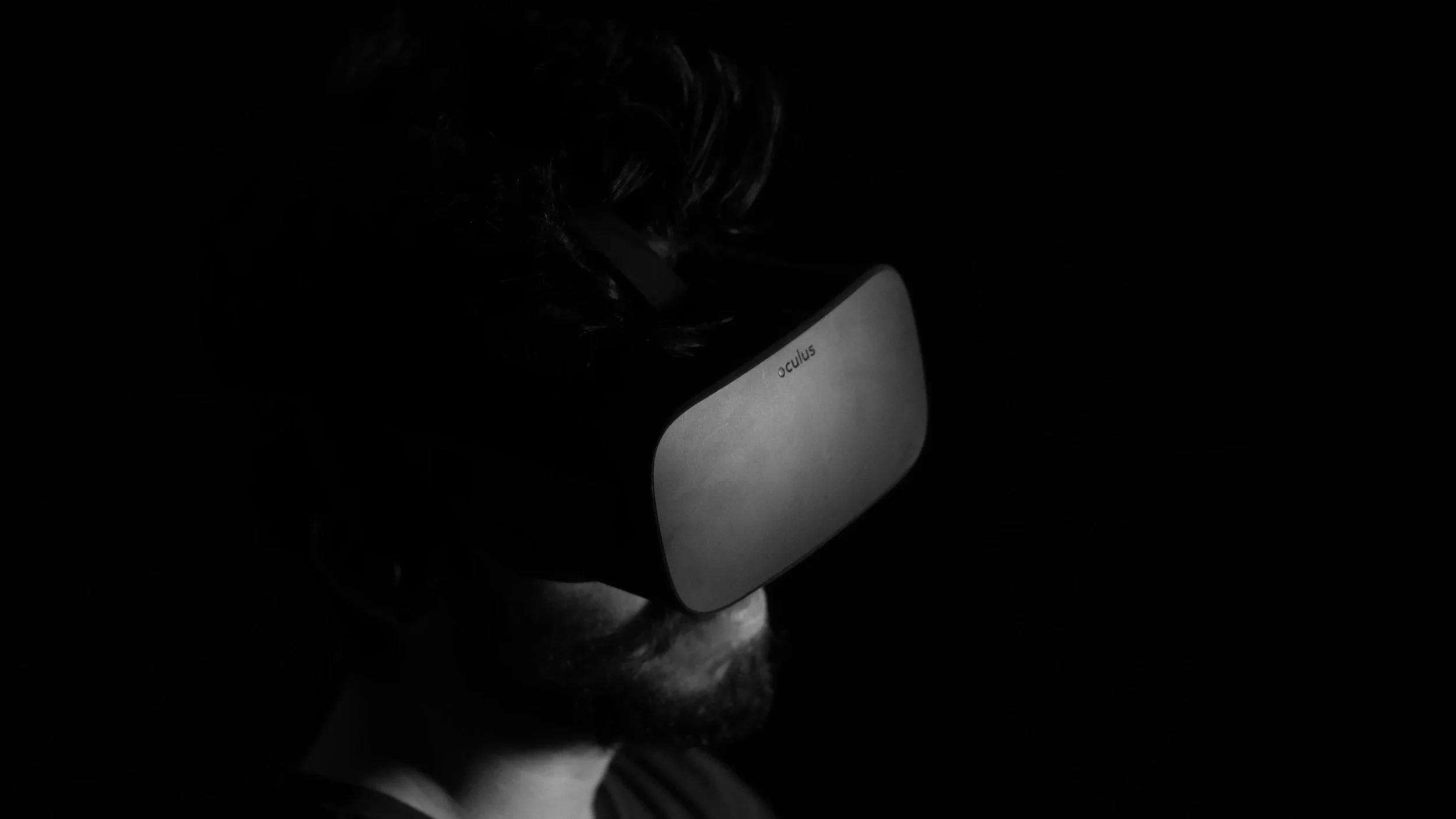 Person wearing an Oculus virtual reality headset in a dark environment.